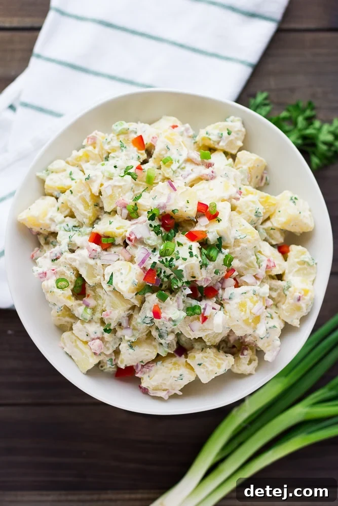 Full white bowl of healthy vegan potato salad, garnished with fresh parsley.