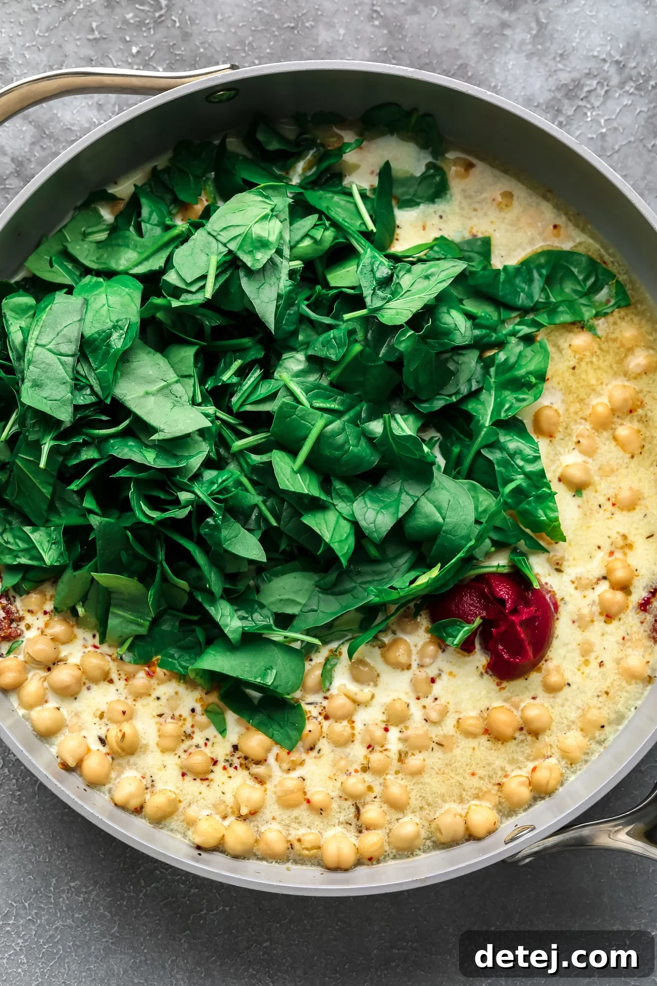 The Chickpea Proposal 4 fresh spinach in a large pan with chickpeas and cream sauce.