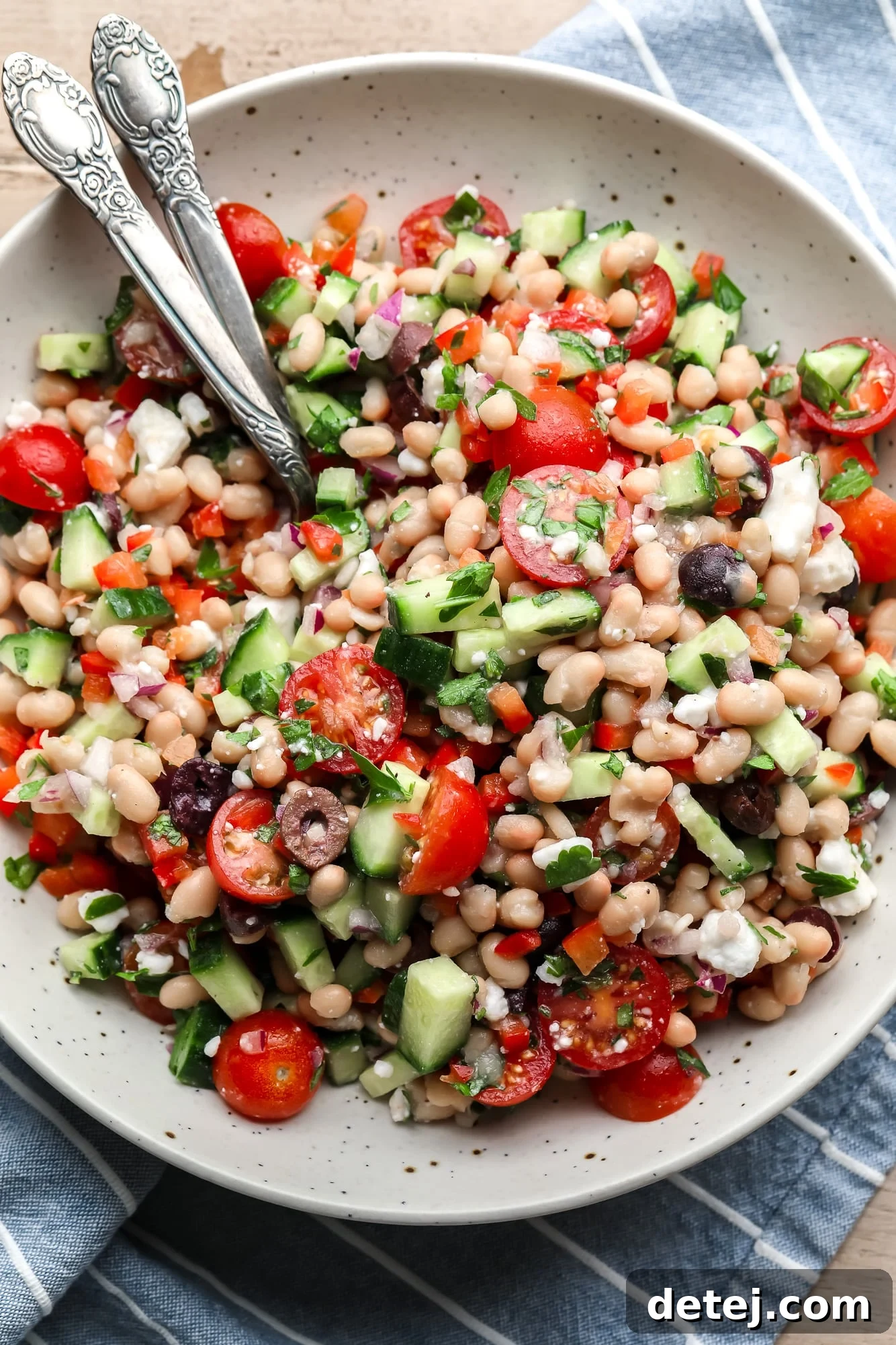 A vibrant Mediterranean white bean salad served in a large white bowl, garnished with fresh herbs.