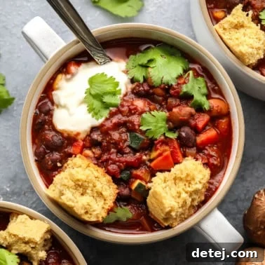 A small bowl of hearty veggie chili topped with crumbled vegan cornbread and fresh cilantro.