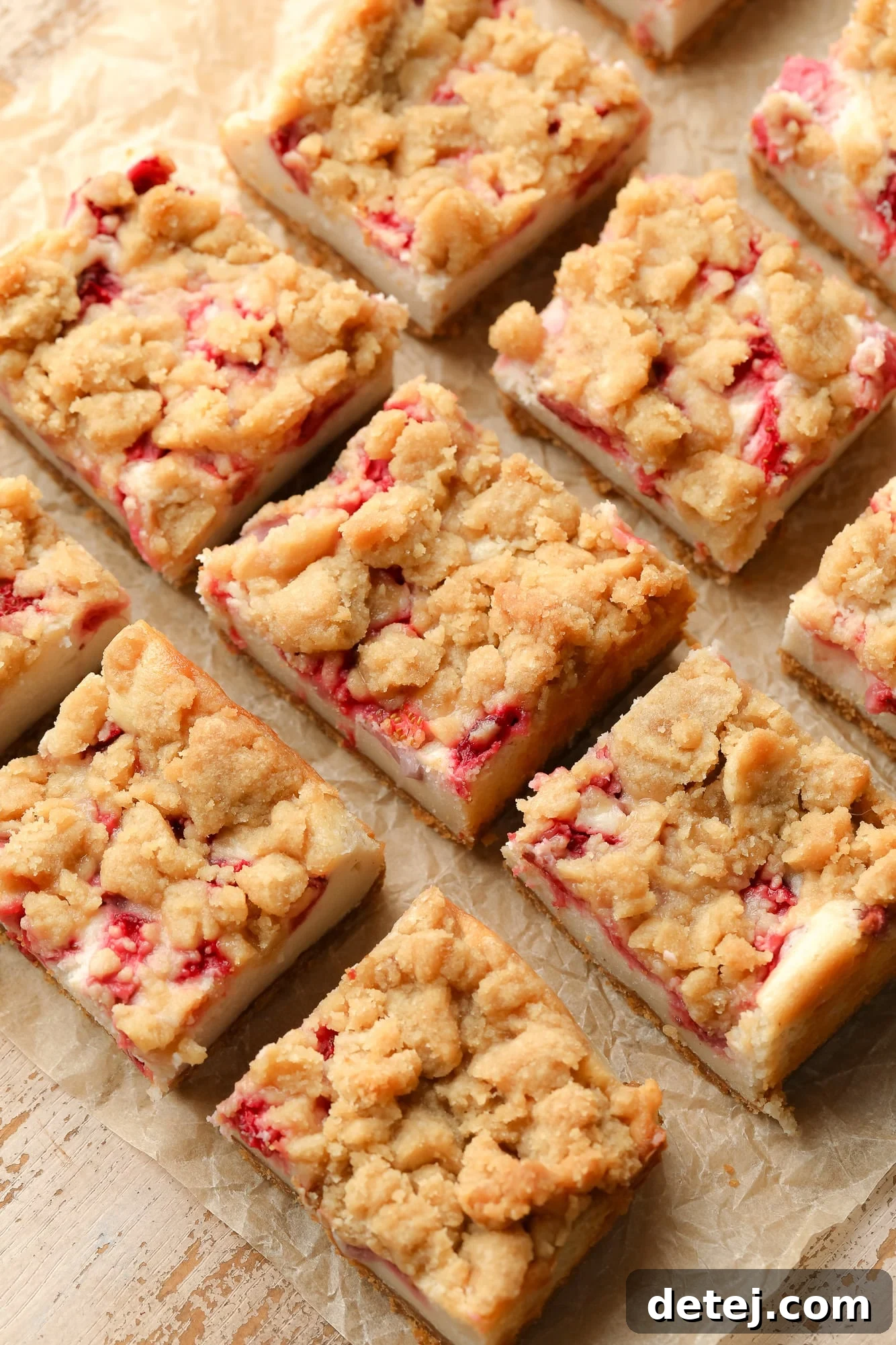 Sliced Vegan Strawberry Cheesecake Crumble Bars arranged neatly on a piece of parchment paper, ready to be served.