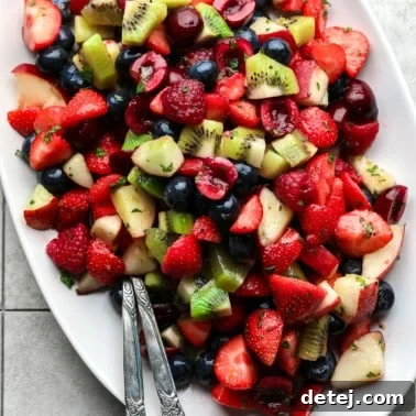 Close up on a glistening fruit salad, showcasing its vibrant colors and fresh appeal on a white serving plate, ready to be enjoyed.