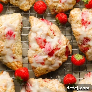 Close up on a baked strawberry scone topped with vanilla glaze.