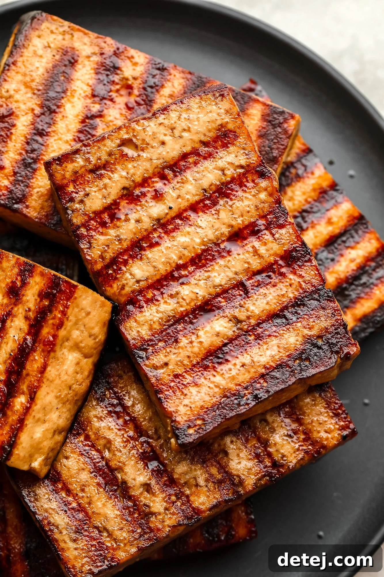 a pile of grilled tofu pieces on a black plate.