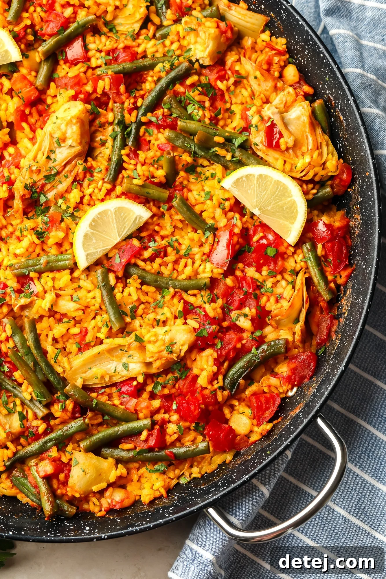 Beautifully garnished vegan paella in a large black paella pan, ready to serve.