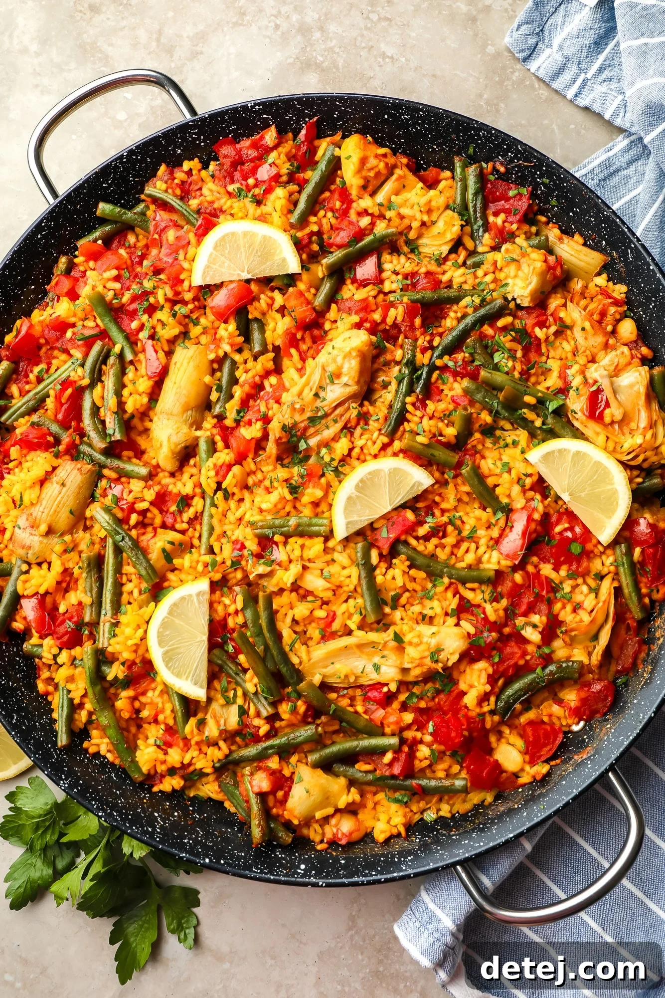 The final vegan paella, beautifully arranged with lemon slices in a large black paella pan, ready to be enjoyed.