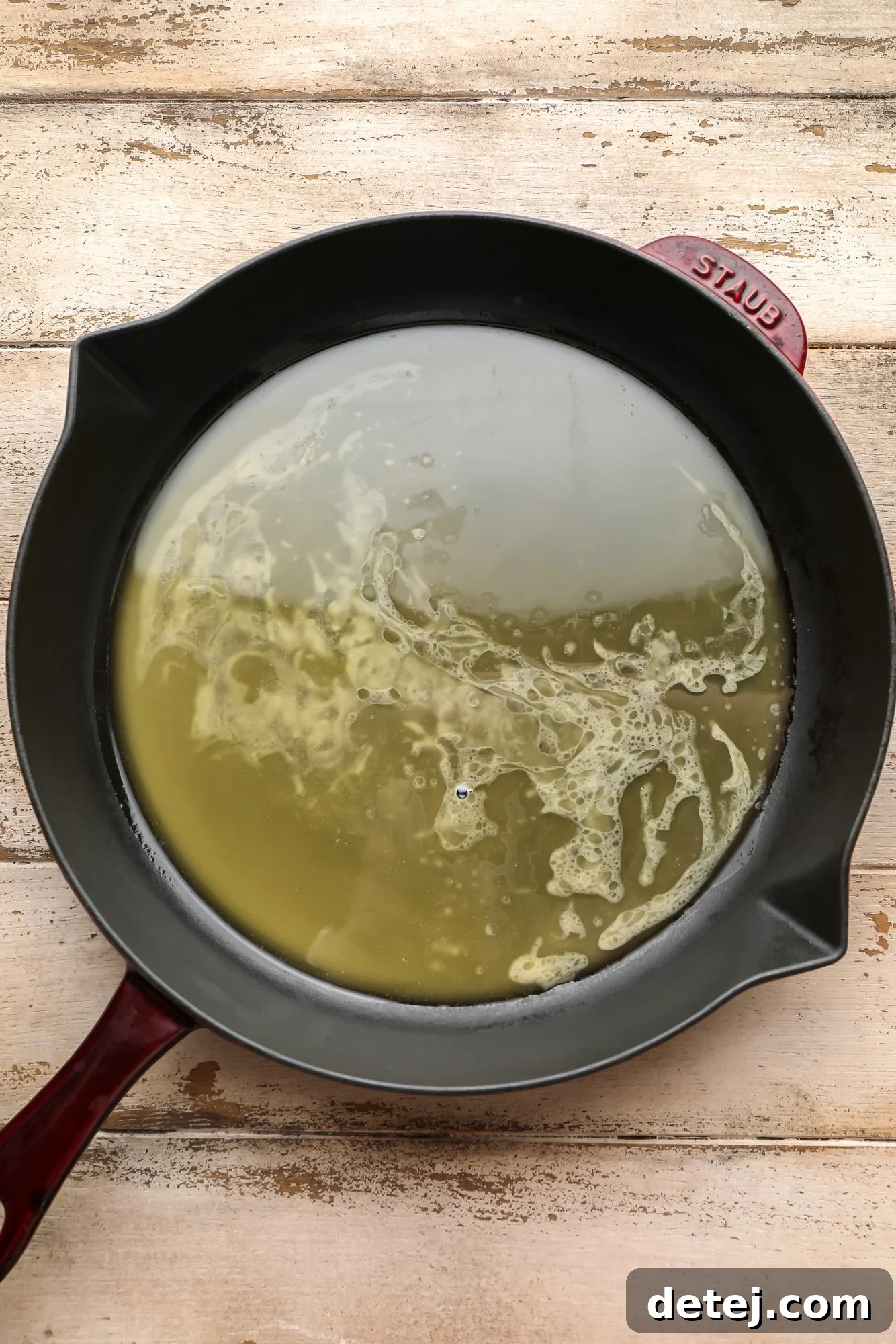 Melted vegan butter pooled in the bottom of a black cast iron skillet, ready for the cobbler dough.