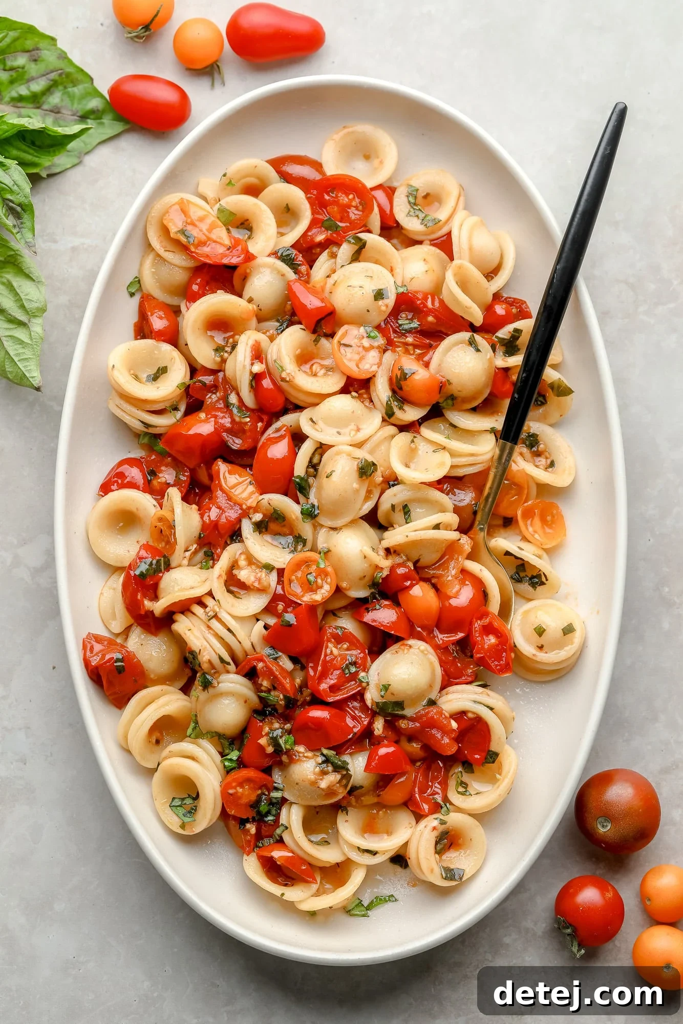 Close-up of a serving of Roasted Tomato Pasta in a white dish, garnished with fresh basil, ready to be enjoyed.