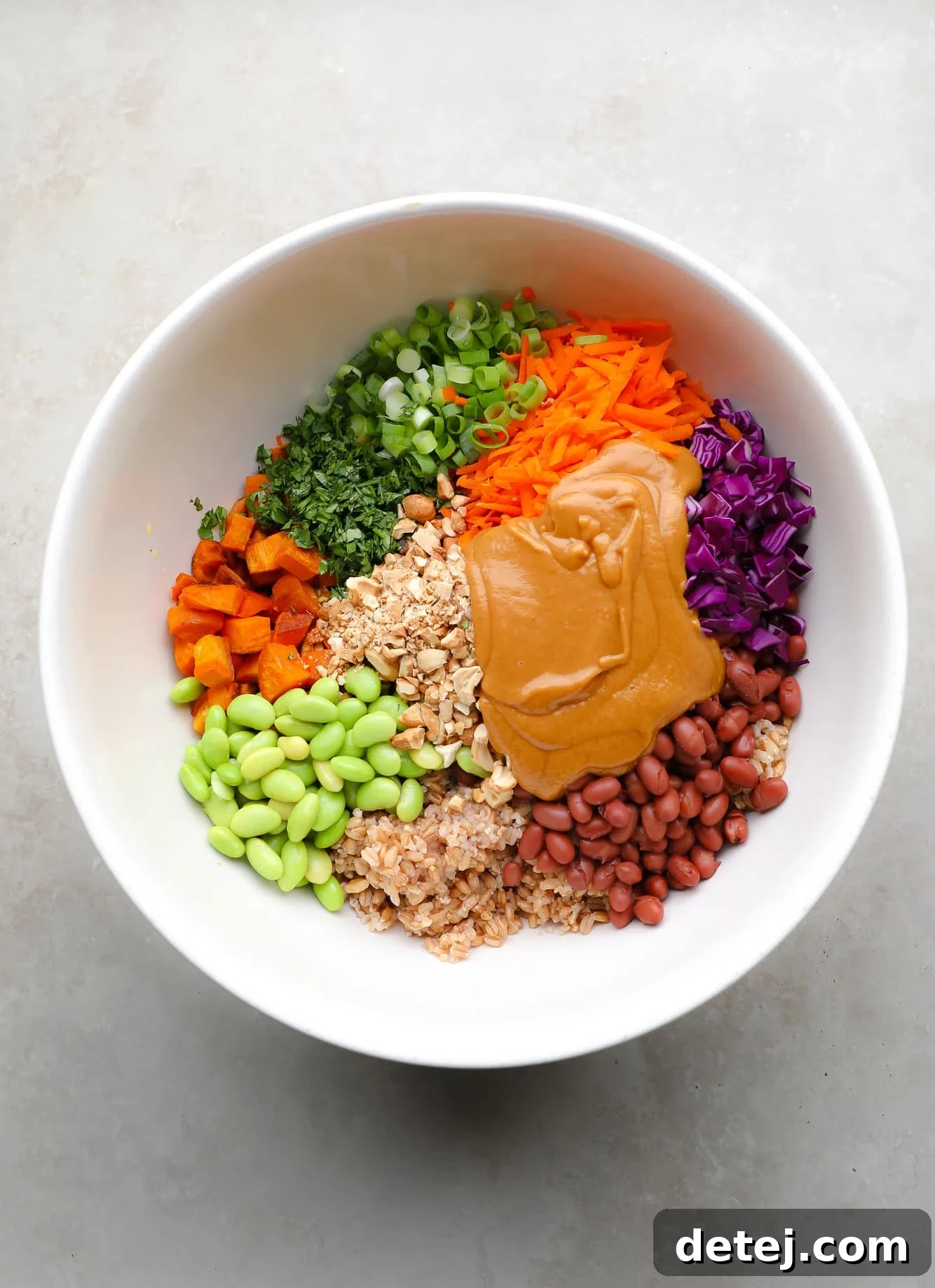 Spicy Peanut Farro Power Bowl 4 ingredients for farro salad and peanut sauce together in a large white bowl.