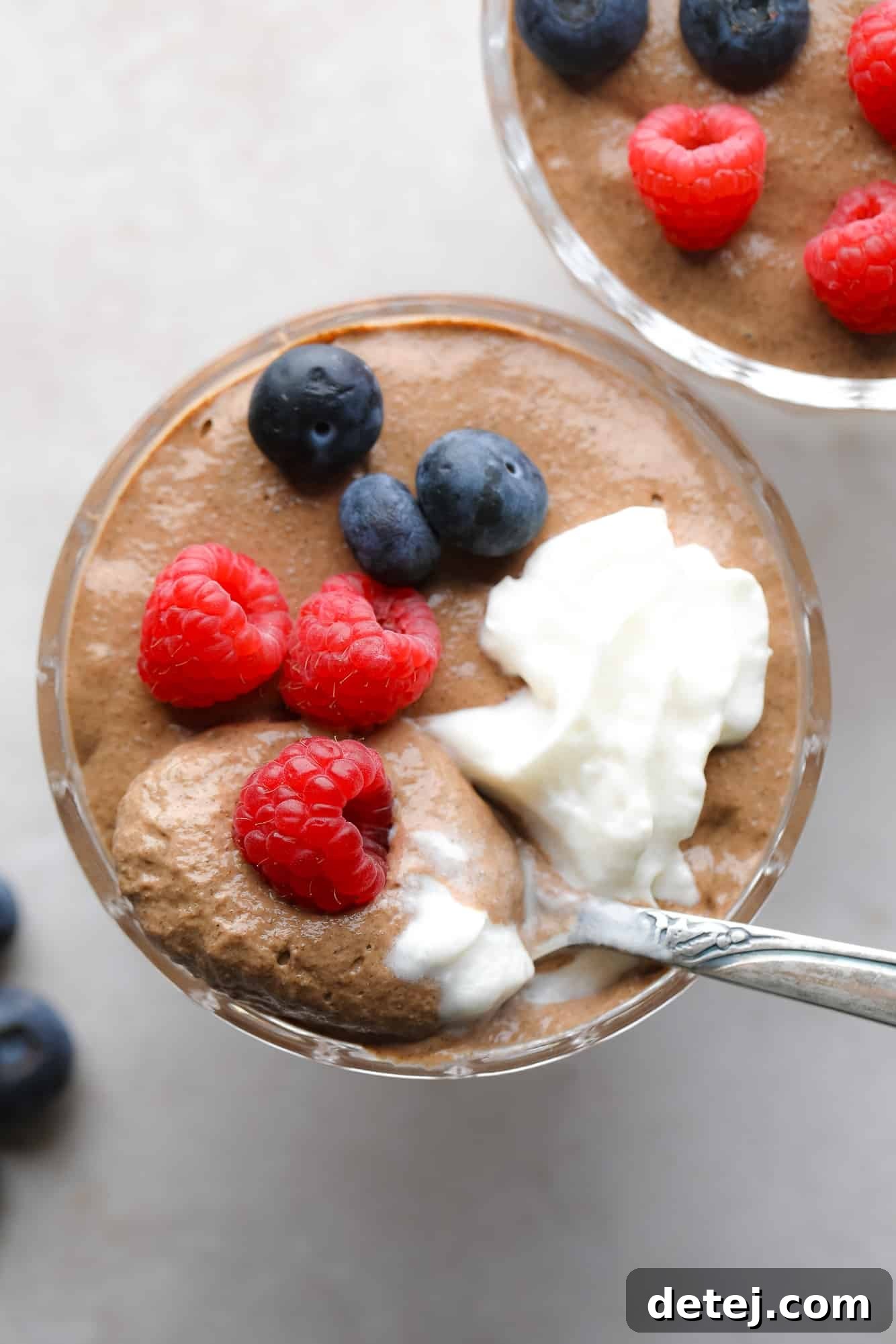 close up on a jar of chocolate chia pudding topped with berries and whipped cream.