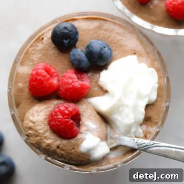 close up on a jar of chocolate chia pudding topped with berries and whipped cream.