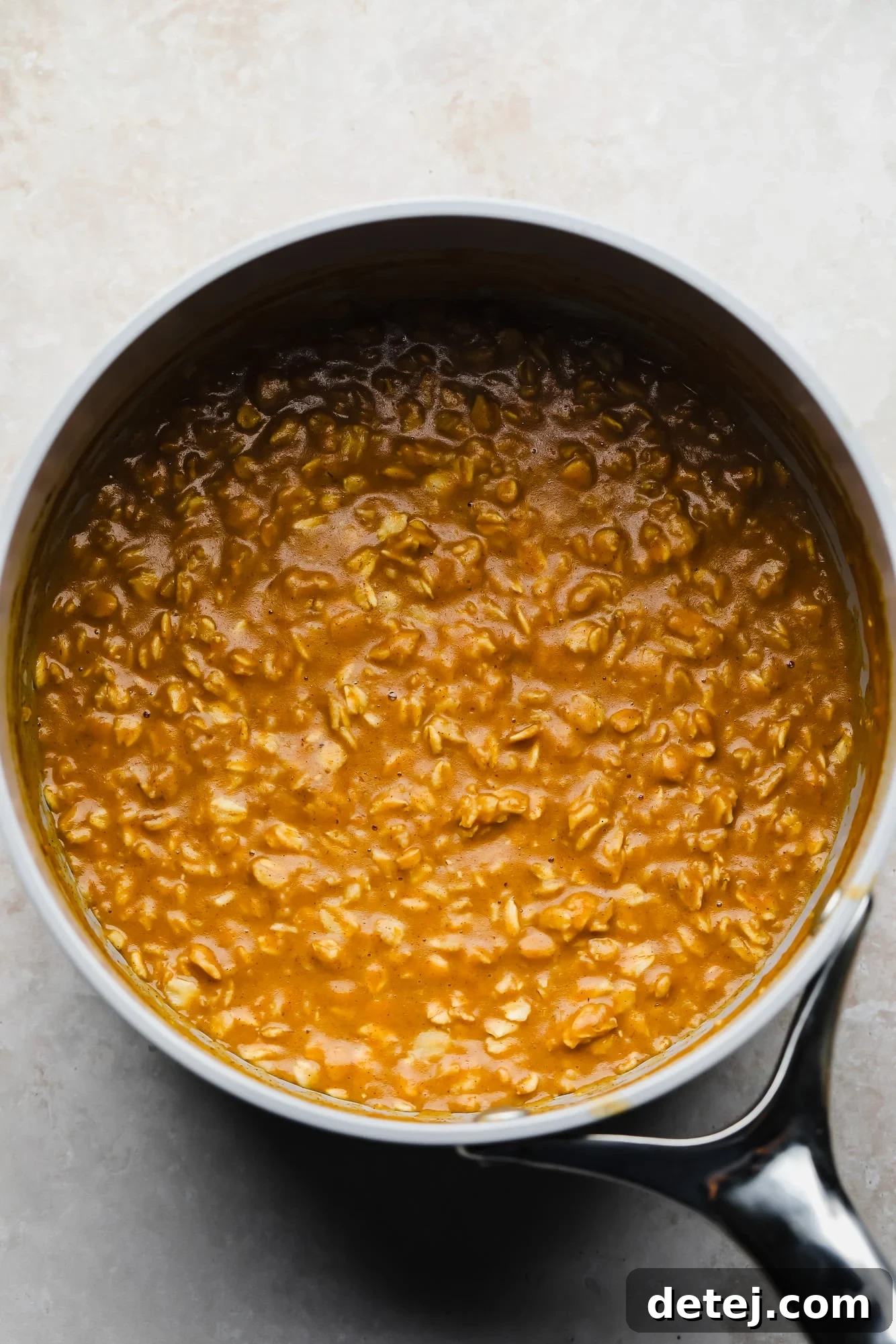 Pumpkin oatmeal simmering gently in a pot on the stovetop, releasing its comforting aroma.