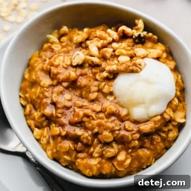 pumpkin oatmeal in a white bowl with a dollop of vegan yogurt on top.