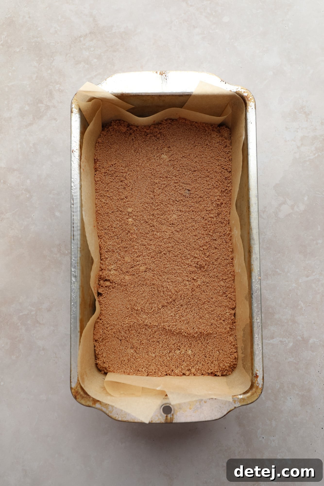 Cinnamon sugar-topped quick bread batter in a loaf pan, showing the first layer.