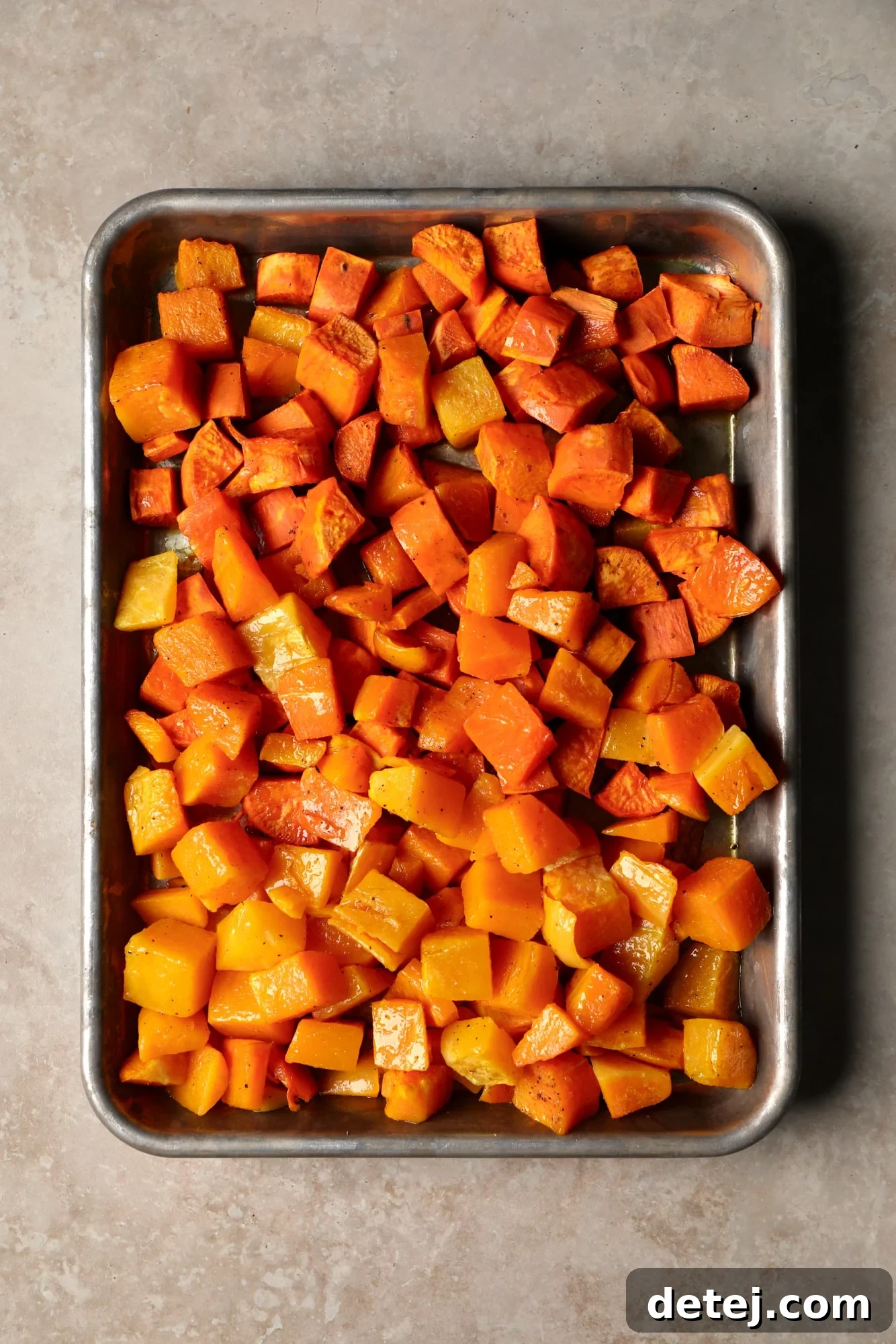 Roasted cubes of vibrant butternut squash and sweet potatoes perfectly laid out on a sheet pan, showcasing their beautiful caramelization, ready to be transformed into a delicious soup.