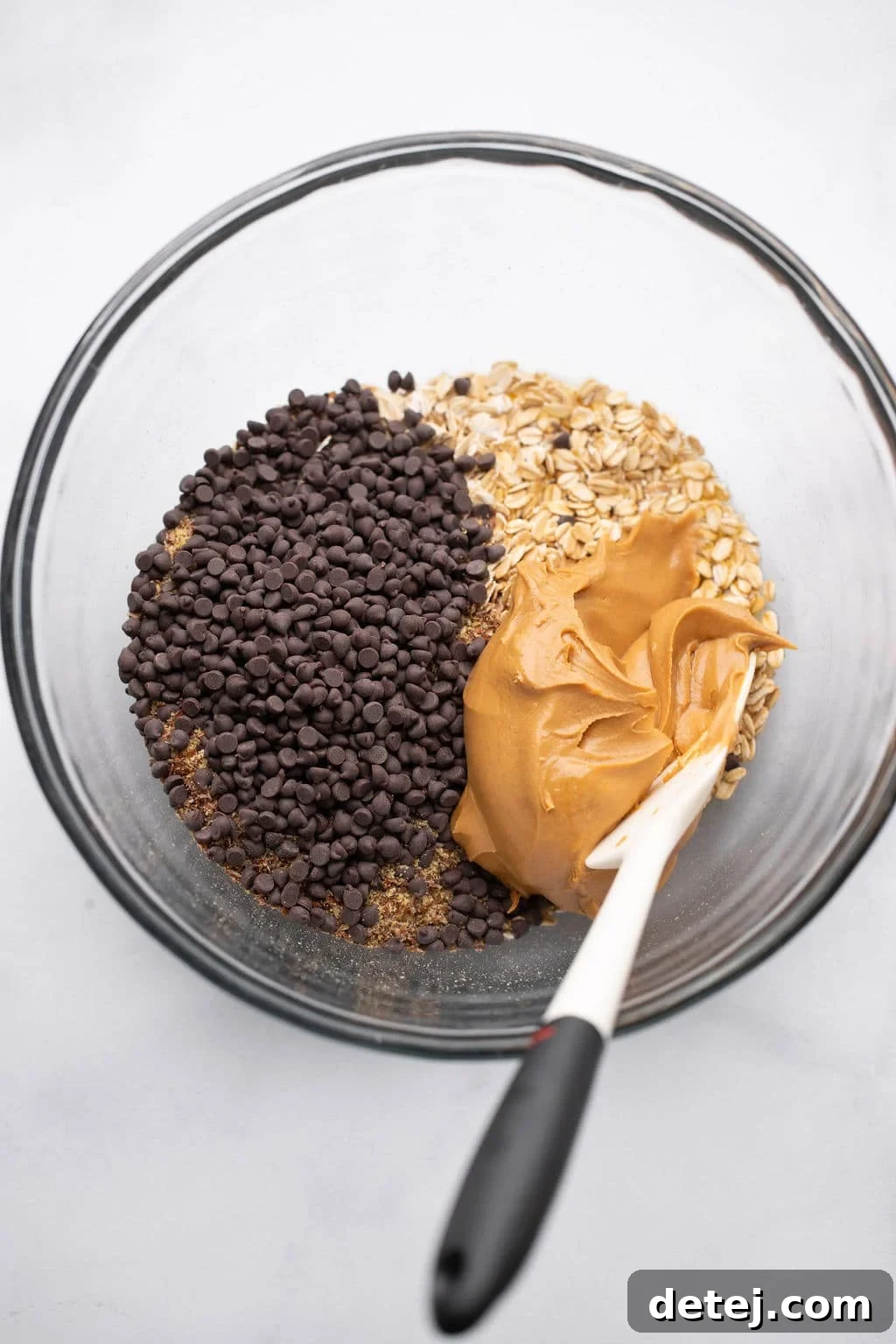 stirring the ingredients for Peanut Butter Energy Balls in a glass bowl.