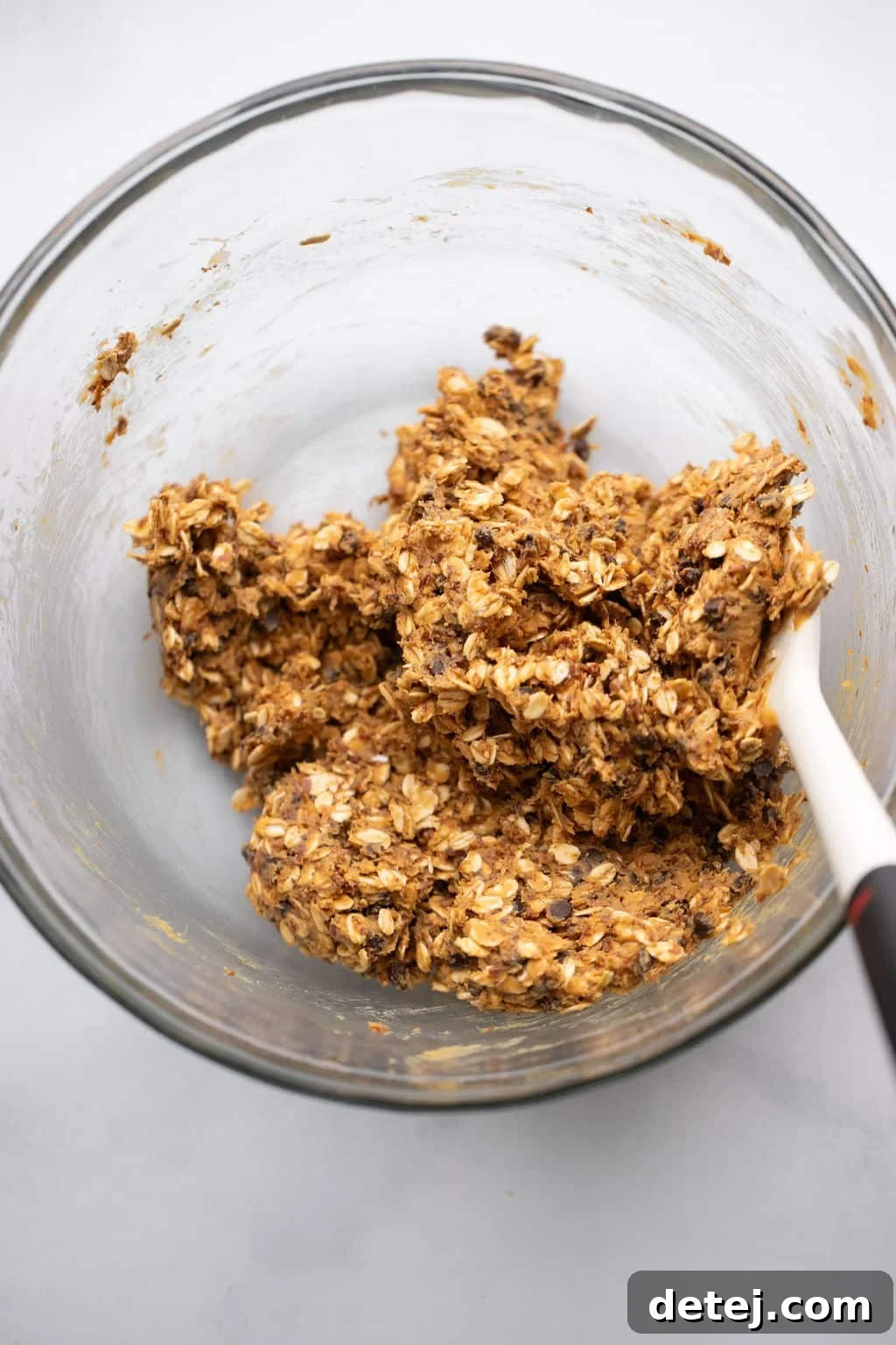 stirring the ingredients for Peanut Butter Energy Balls in a glass bowl.