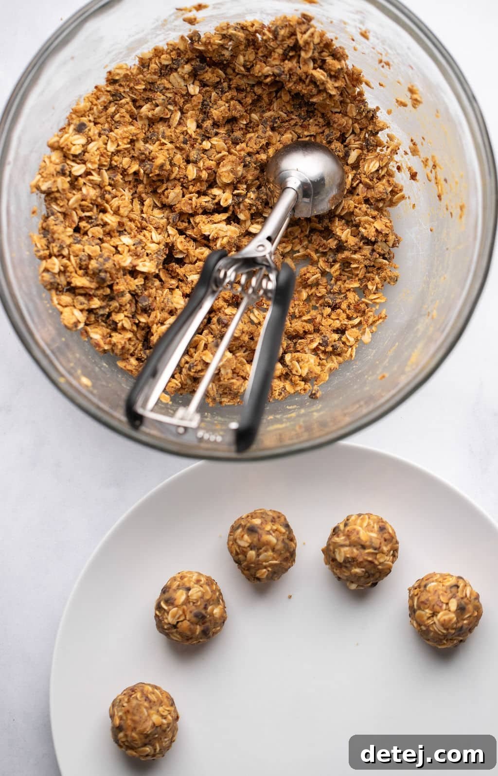 a glass bowl with an oat-peanut butter mixture beside rolled peanut butter energy balls on a white plate.