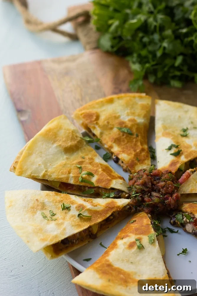 Close-up of freshly cut Cheesy Vegan Quesadillas, revealing the melted cashew cheese and vegetable filling