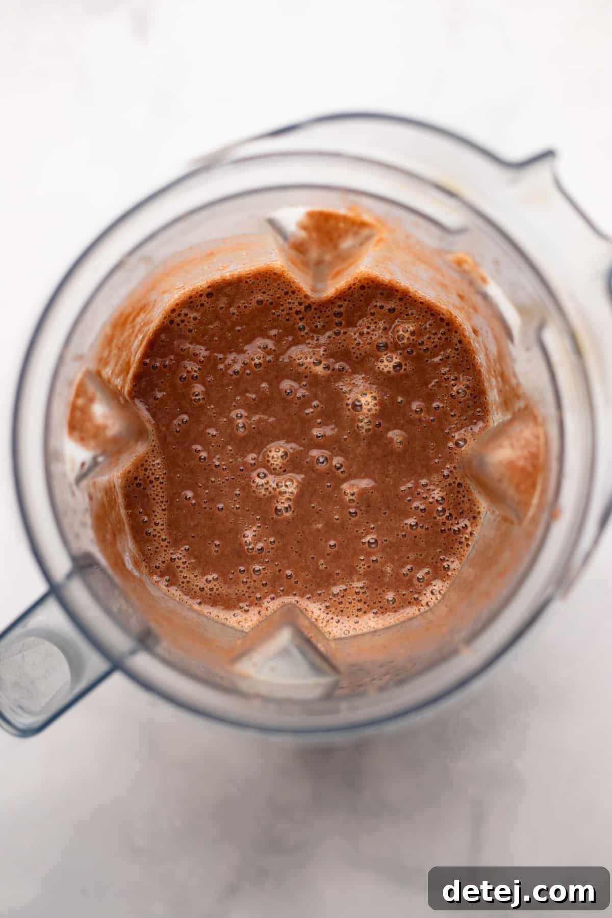 Creamy black bean sauce being blended in a high-speed blender, showcasing its smooth texture and rich color, ready to elevate the enchiladas.