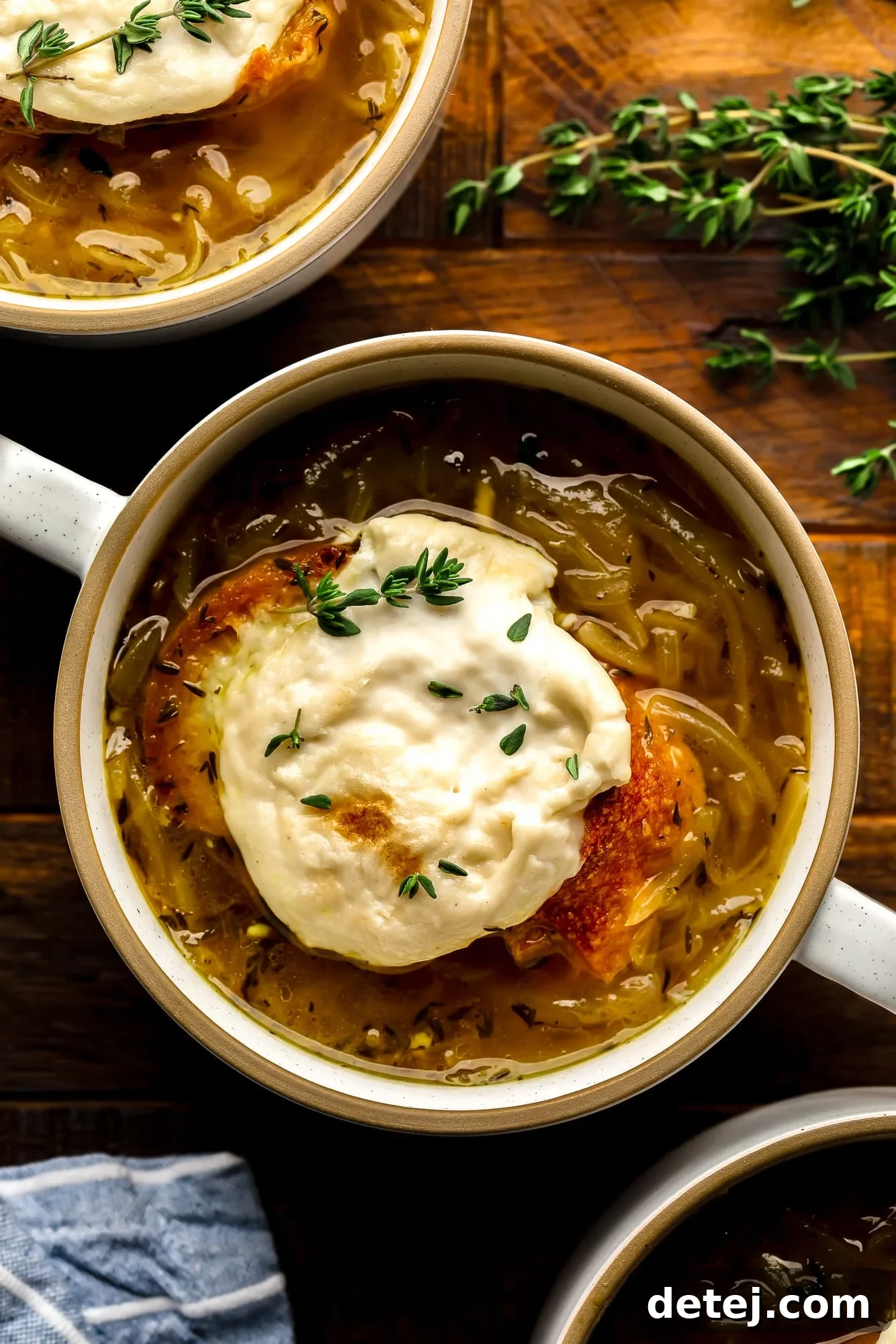 a bowl of Vegan French Onion Soup topped with toasted vegan cheesy bread.