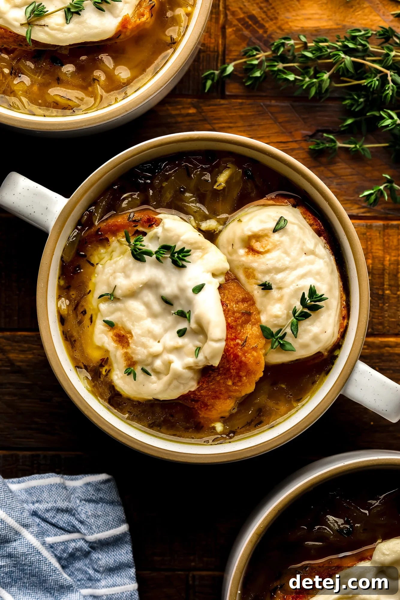 a bowl of Vegan French Onion Soup topped with toasted vegan cheesy bread.