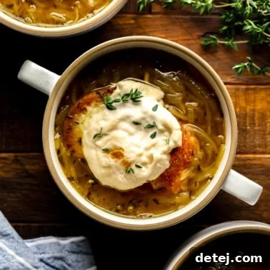 a bowl of Vegan French Onion Soup topped with toasted vegan cheesy bread.