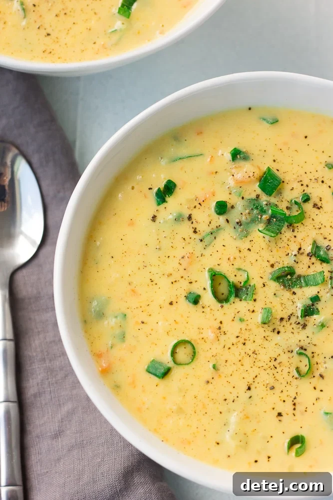 An overhead shot of a vibrant bowl of creamy vegan cauliflower kale soup, perfectly presented with a spoon and fresh garnishes.