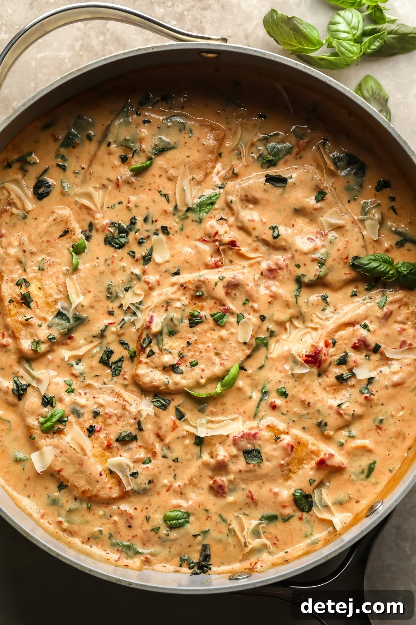A large skillet of Vegan Marry Me Tofu, showcasing crispy pan-fried tofu triangles nestled in a rich, creamy sun-dried tomato sauce with spinach.