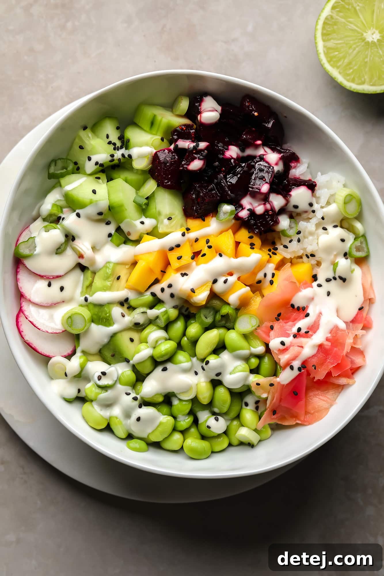 A vibrant vegan beet poke bowl topped with marinated beets, fresh mango, crisp radishes, edamame, cucumber, pickled ginger, and a generous drizzle of wasabi mayo.