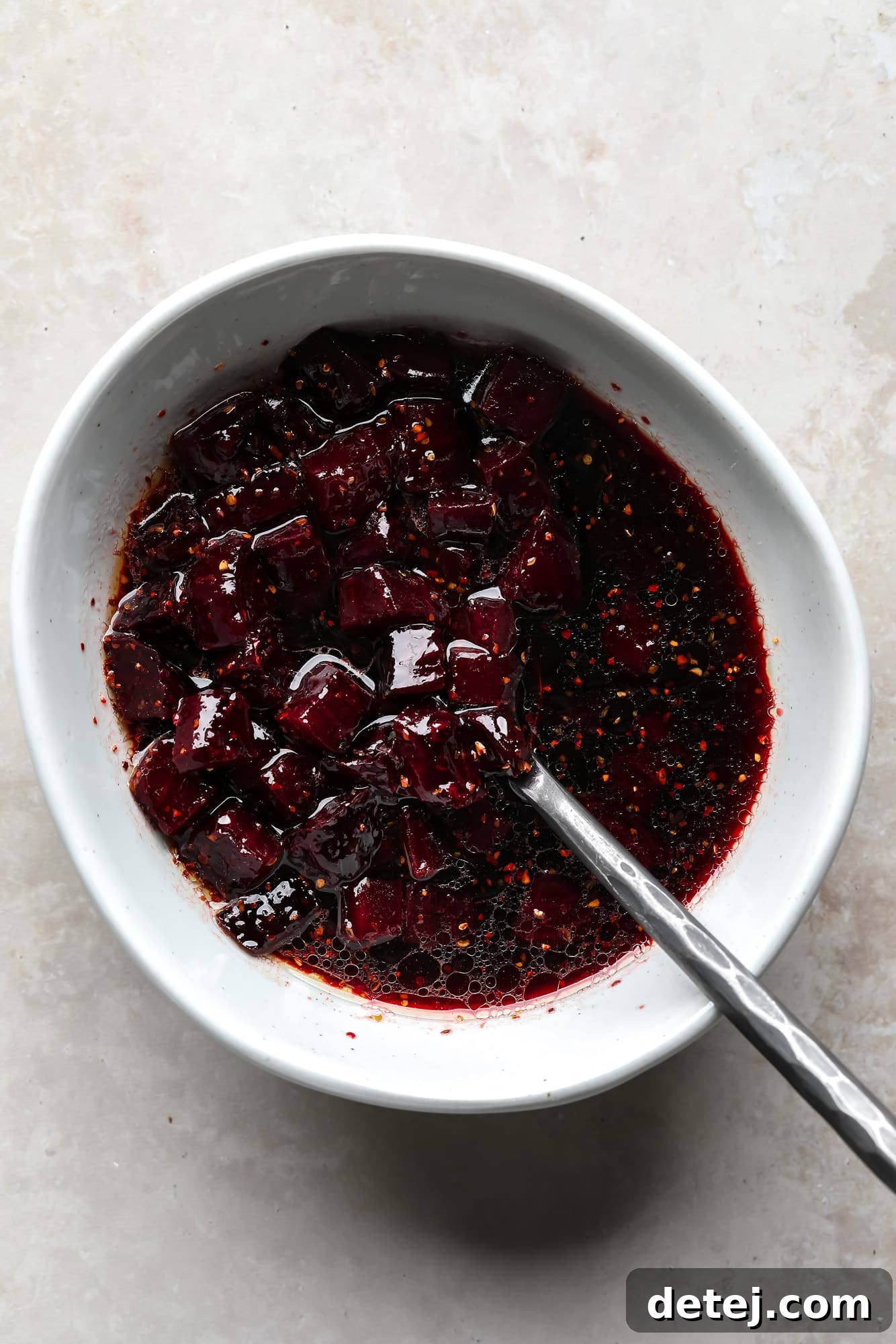 Roasted beets soaking in a vibrant dark red marinade in a white ceramic bowl, ready to be added to poke bowls.