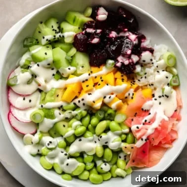 A beet poke bowl topped with marinated beets, mango, radishes, edamame, cucumber, pickled ginger, and wasabi mayo.
