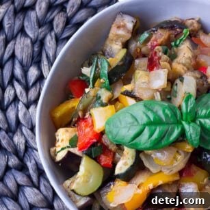 A close-up shot of the finished Roasted Ratatouille in a bowl, showing the vibrant colors and tender texture of the vegetables, garnished with fresh basil.