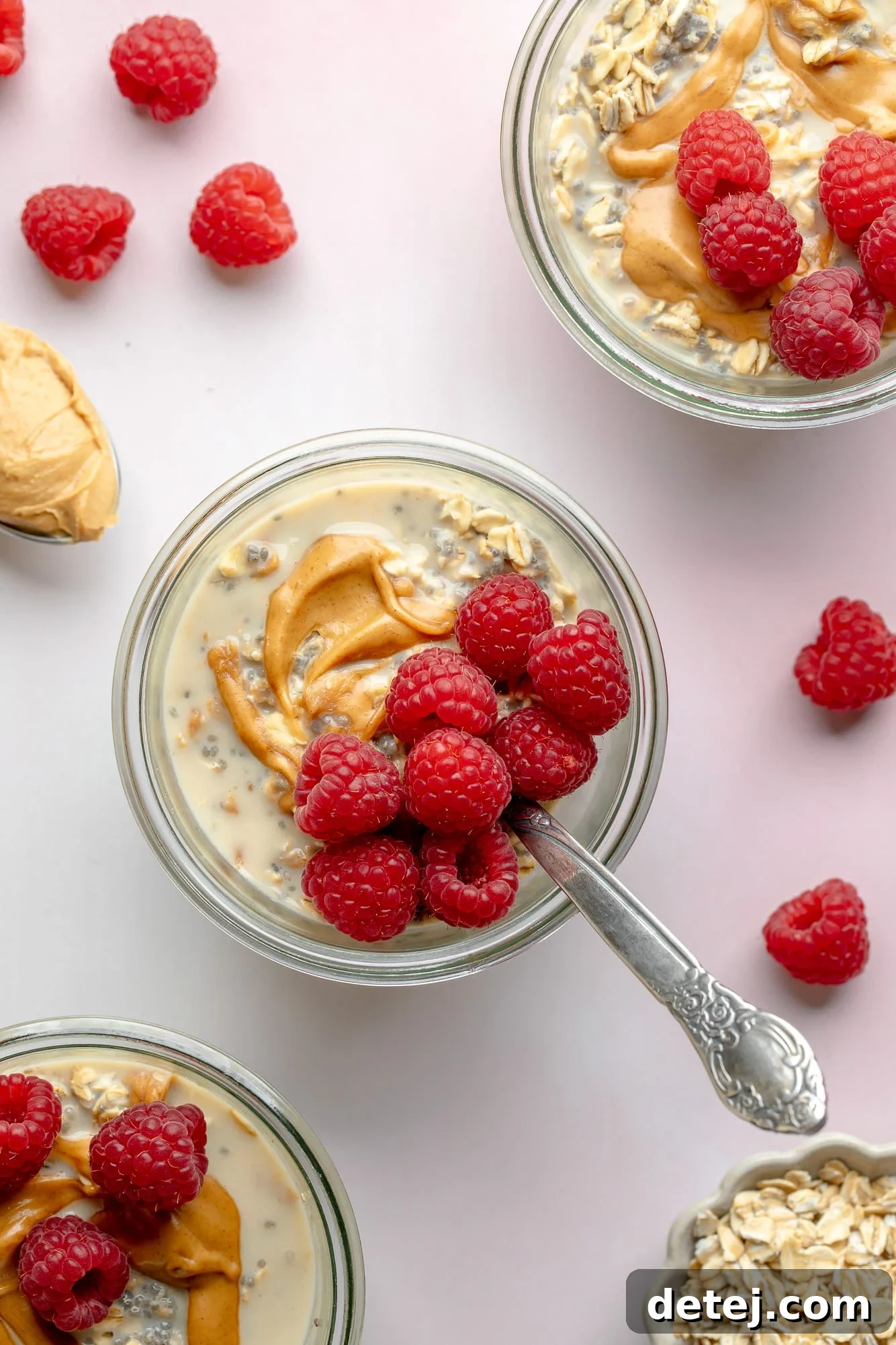 Overhead view of jars of peanut butter overnight oats, elegantly topped with fresh raspberries, showcasing a vibrant and healthy breakfast option.
