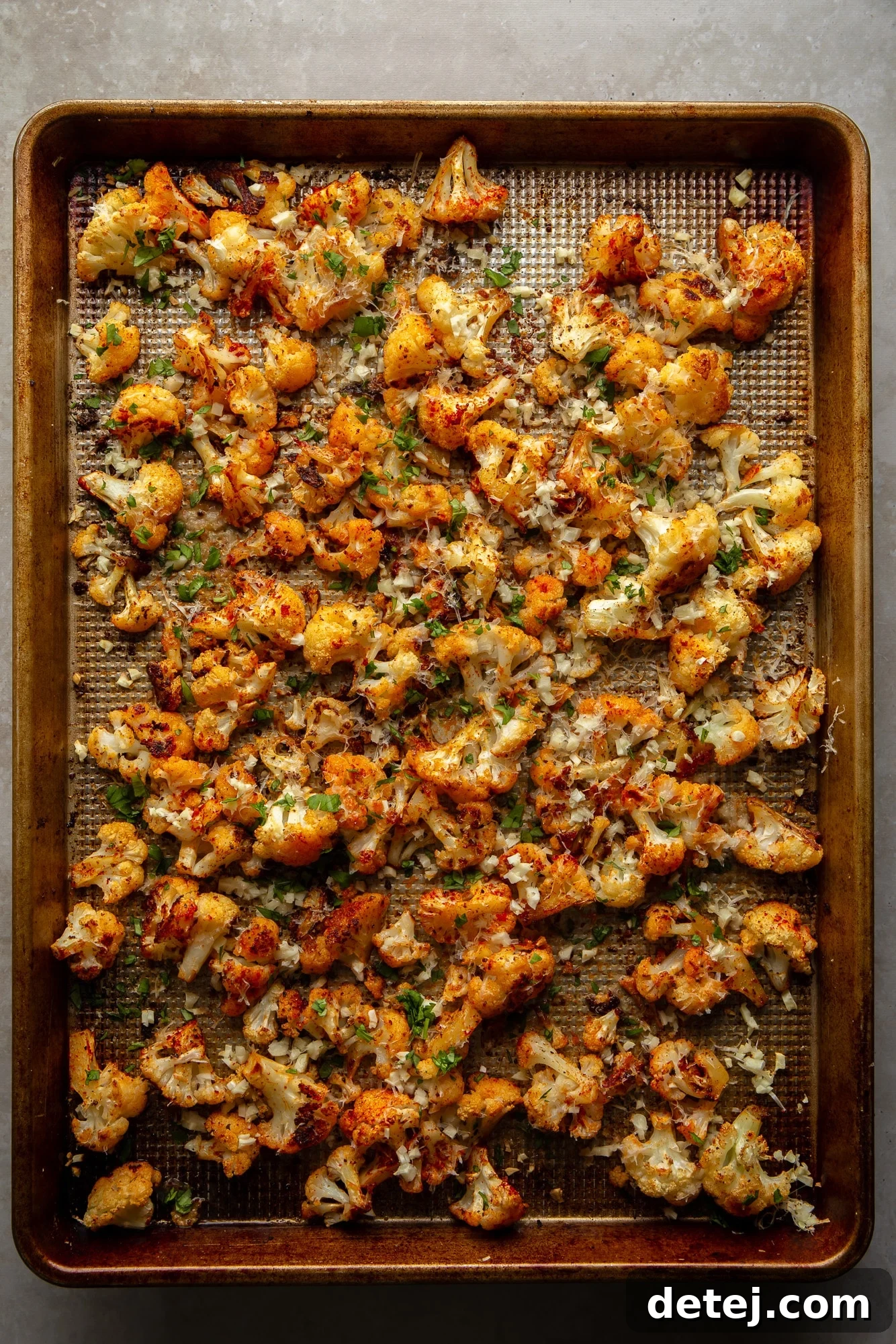 roasted cauliflower garnished with garlic and parmesan on a baking sheet.