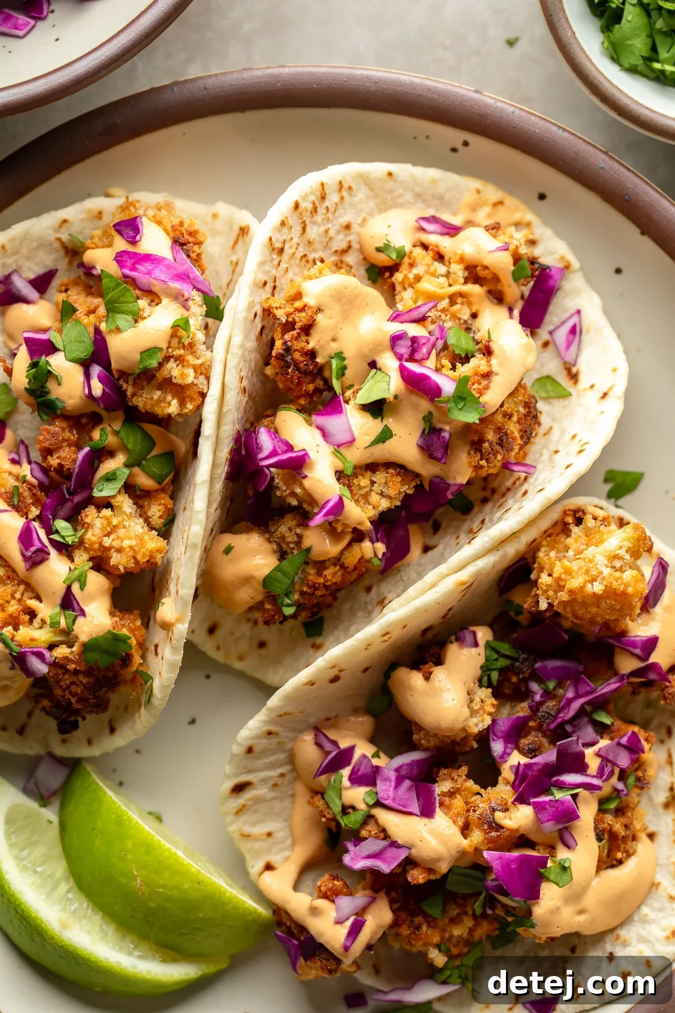 A close-up shot of three vibrantly topped crispy cauliflower tacos, showcasing their texture and fresh ingredients.