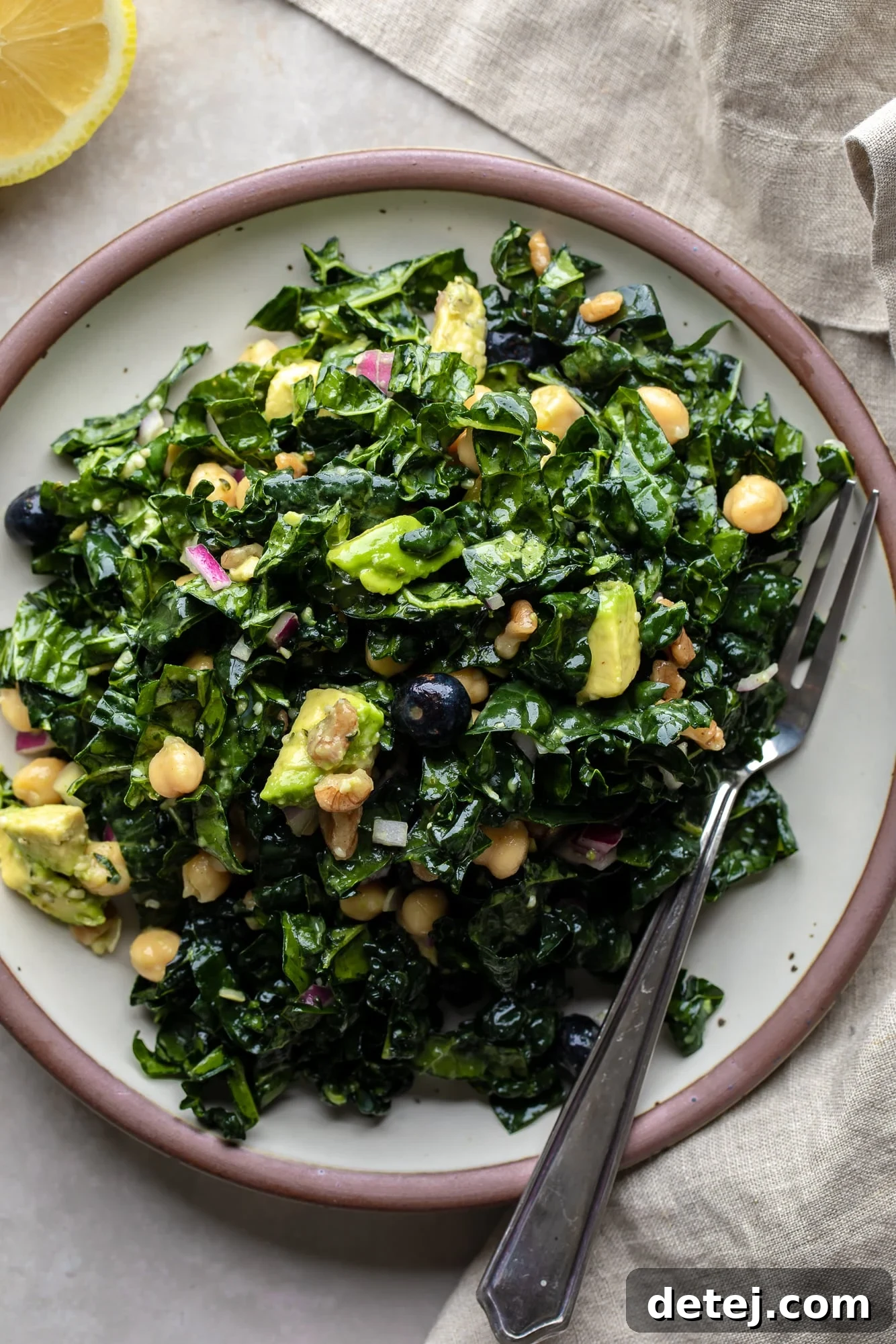 A vibrant kale salad served on a pristine white plate, showcasing its fresh ingredients and inviting colors.