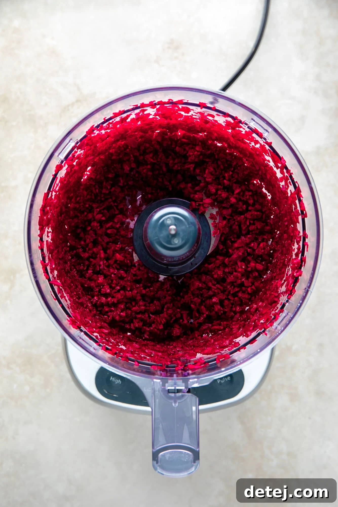 Ruby Red Bean Burgers 3 Finely shredded red beets inside a food processor bowl, displaying their vibrant color and ready to be incorporated into the burger mixture.