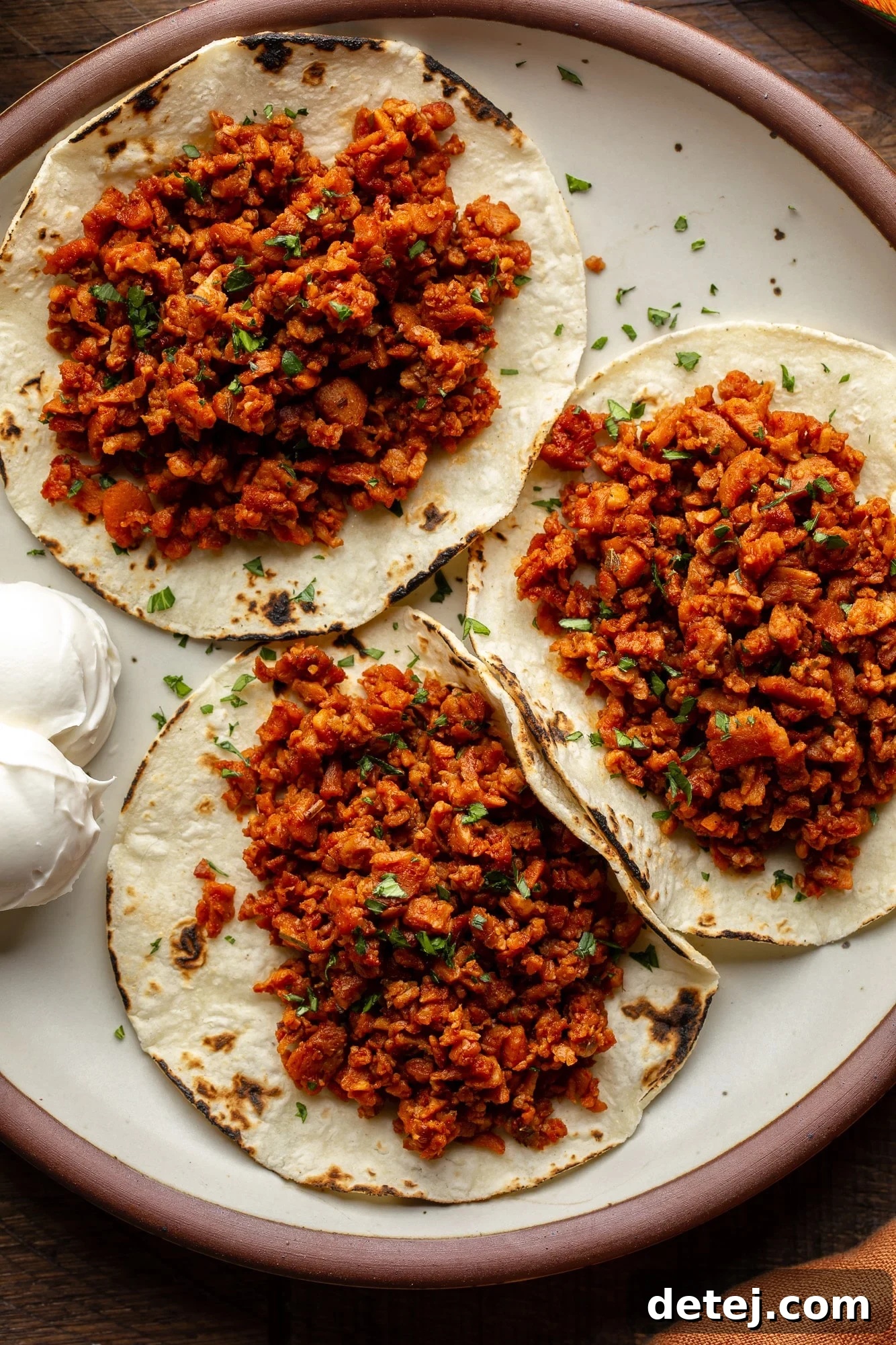 Plant-Based Chorizo 5 A vibrant plate featuring three soft tortillas generously filled with homemade vegan chorizo, garnished with fresh cilantro and lime, ready to be enjoyed.