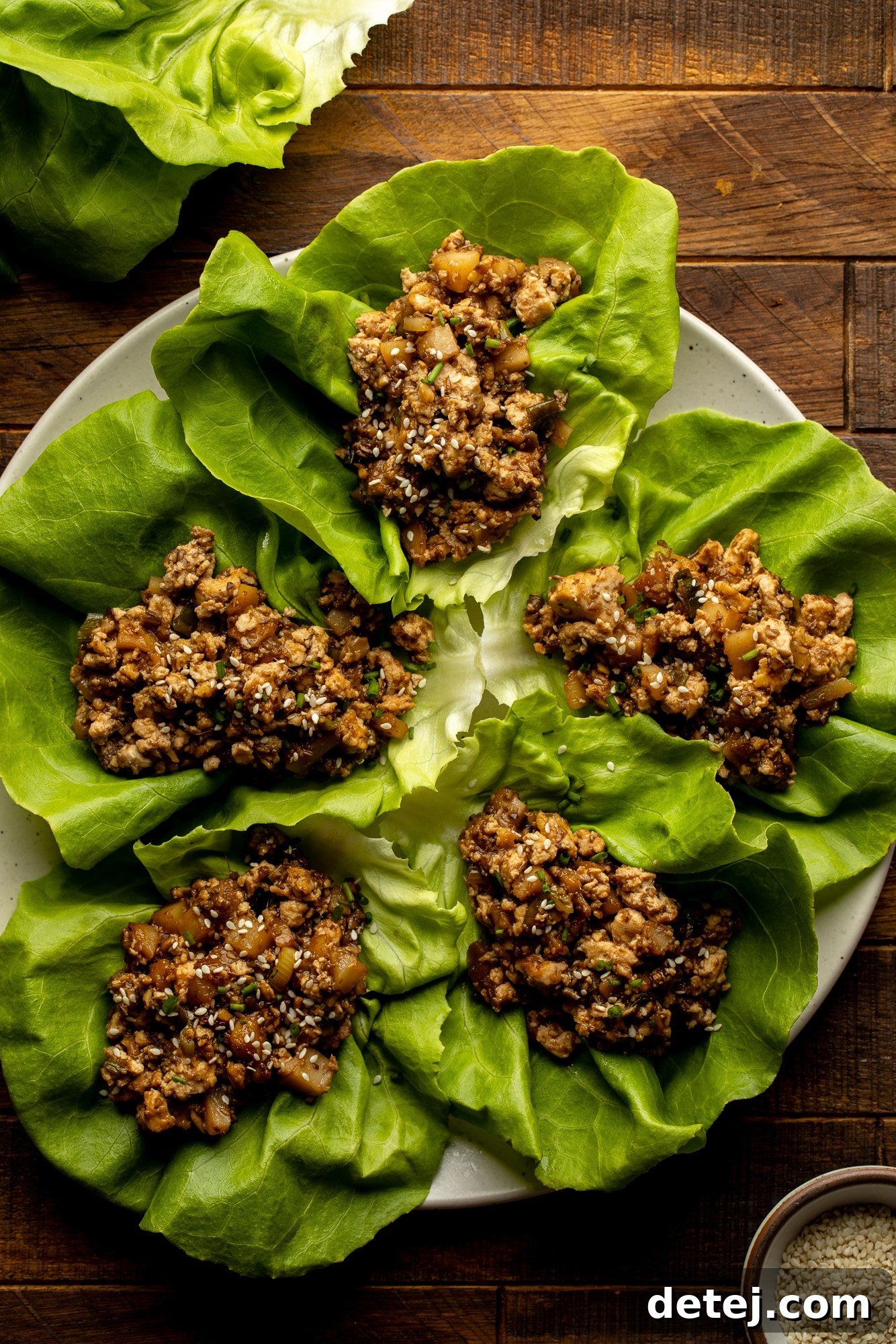 Top-down shot of a beautifully arranged plate of Tofu Lettuce Wraps, showcasing multiple vibrant lettuce cups filled with the savory tofu mixture, garnished with fresh herbs and a light sauce, ready to be enjoyed.