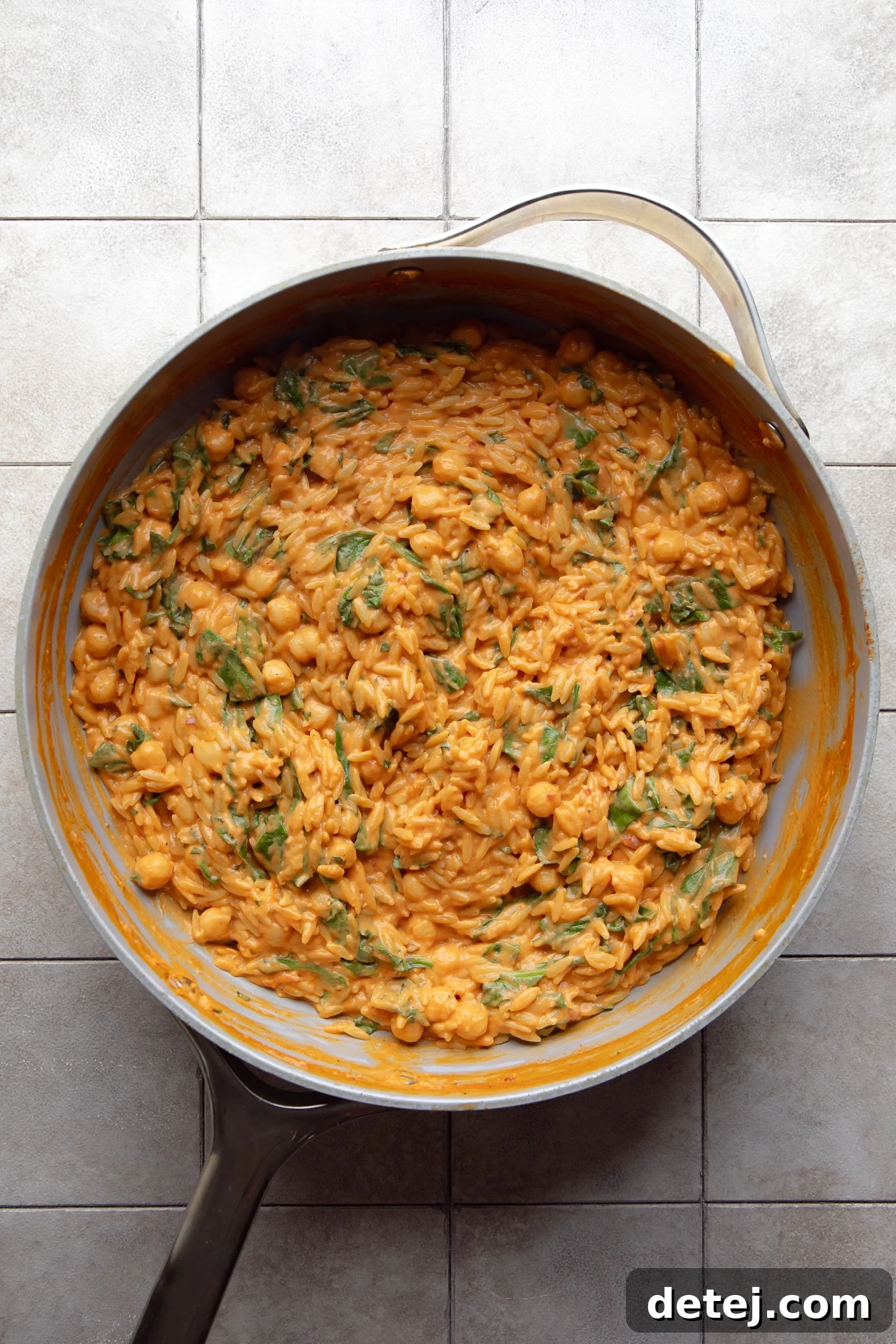 The finished creamy tomato orzo dish in a skillet, garnished with fresh herbs, ready to be served.