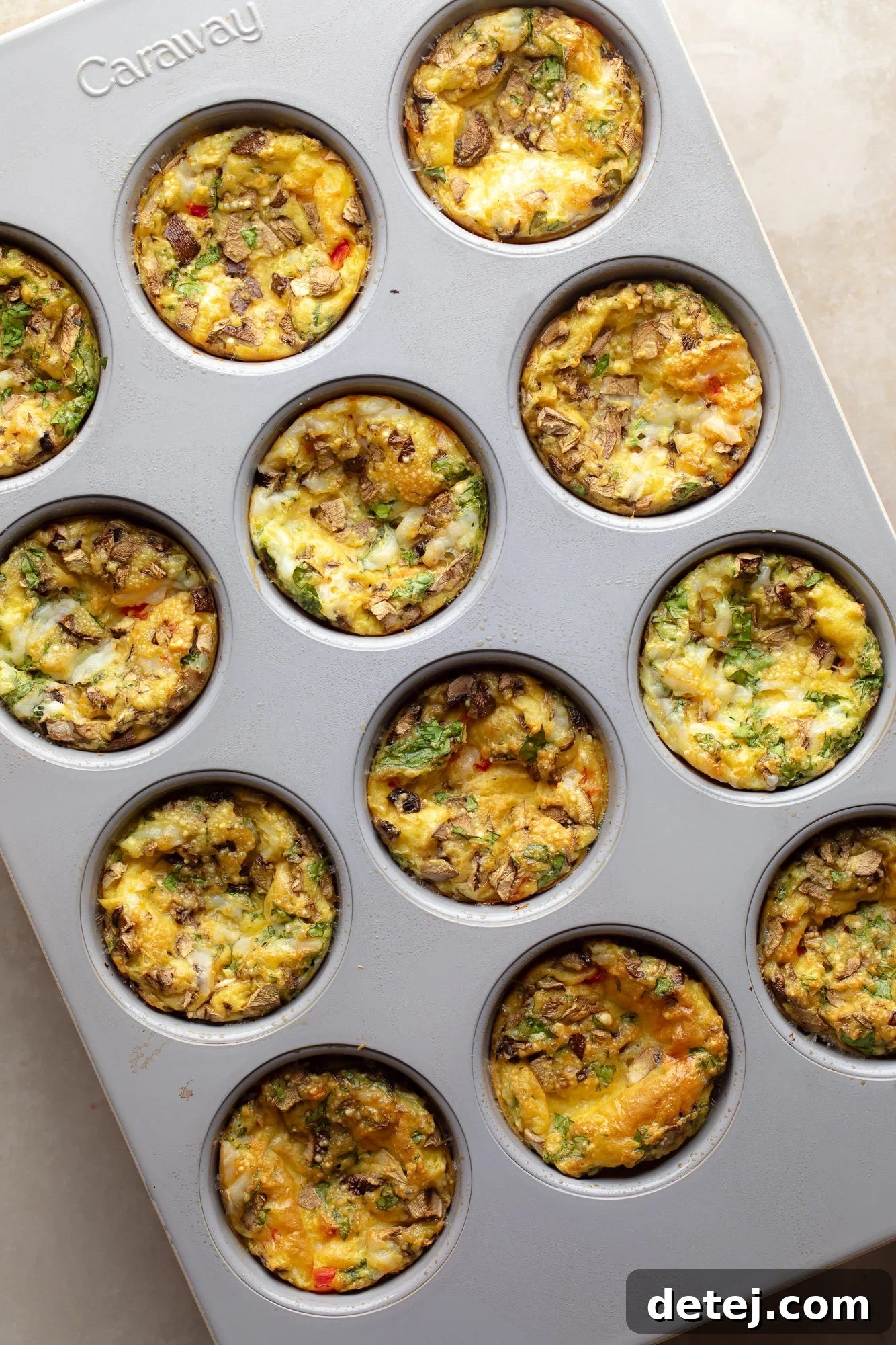 Cooked vegan egg muffins still in a muffin tin, showing their golden-brown, domed tops and perfectly set texture, ready to be removed and enjoyed.