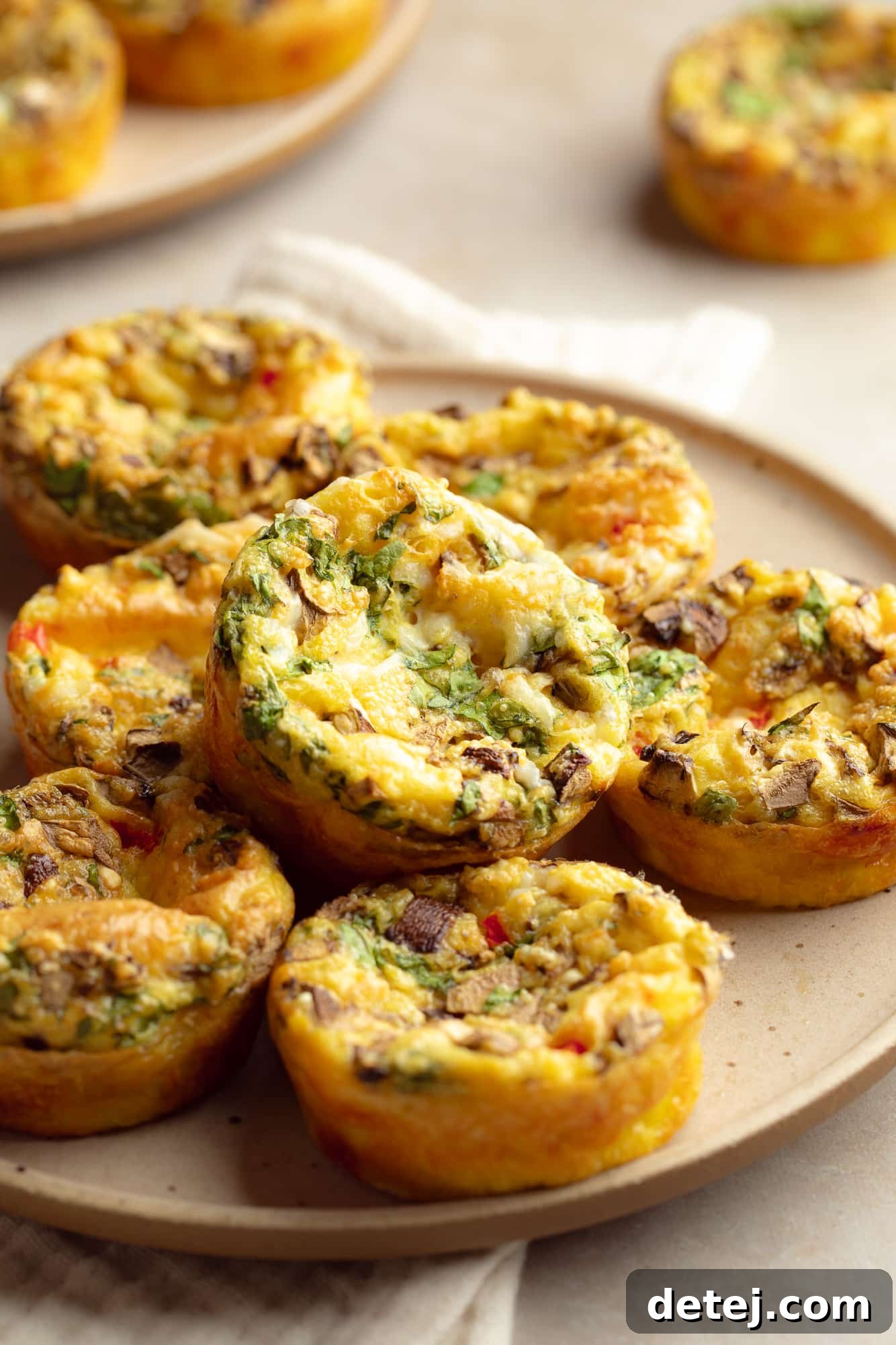 Close-up of a stack of fluffy vegan egg muffins on a white plate, revealing the texture and colorful vegetable fillings. Ideal for a wholesome vegan breakfast.