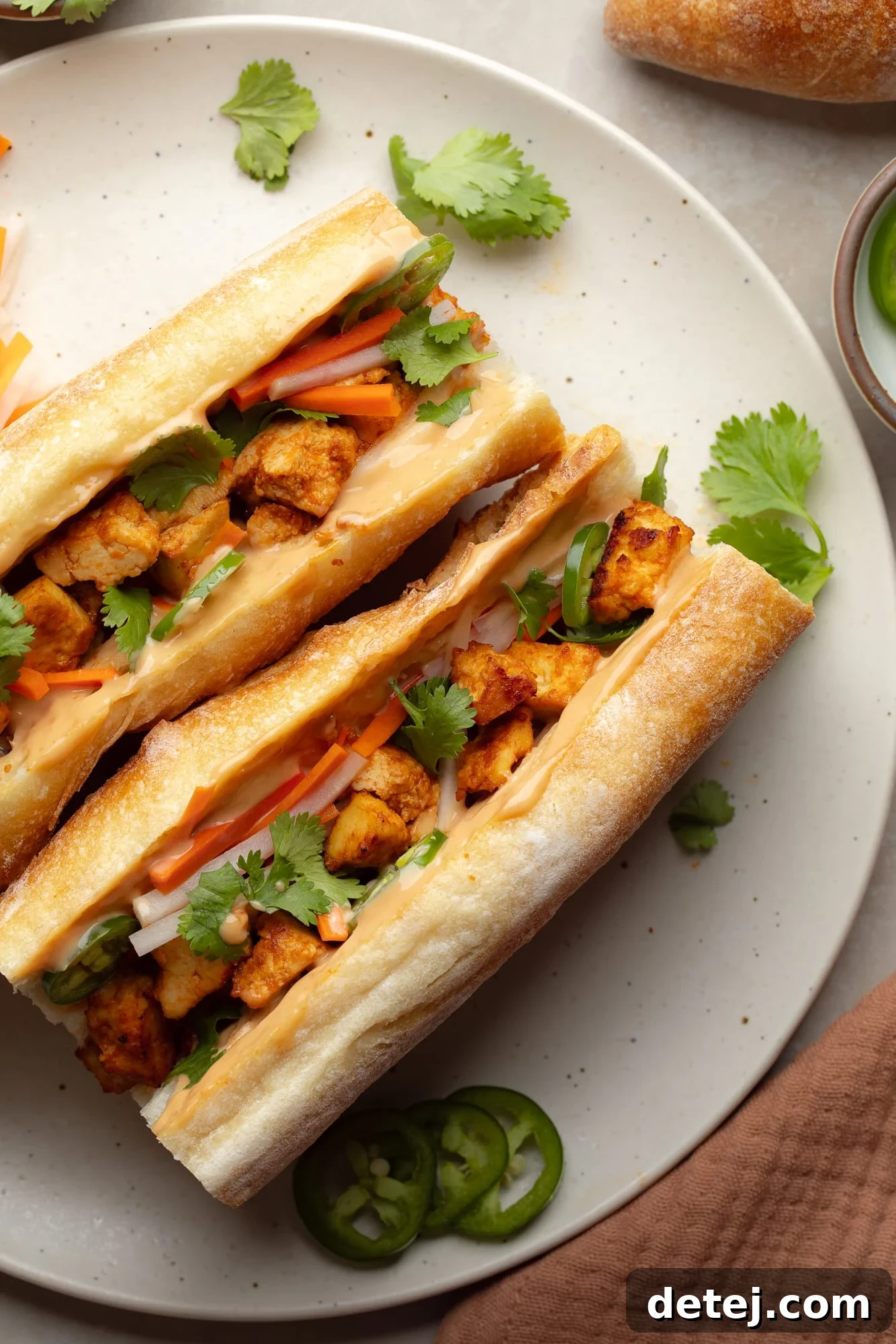 overhead view of two vegan banh mi sandwiches on a white plate.