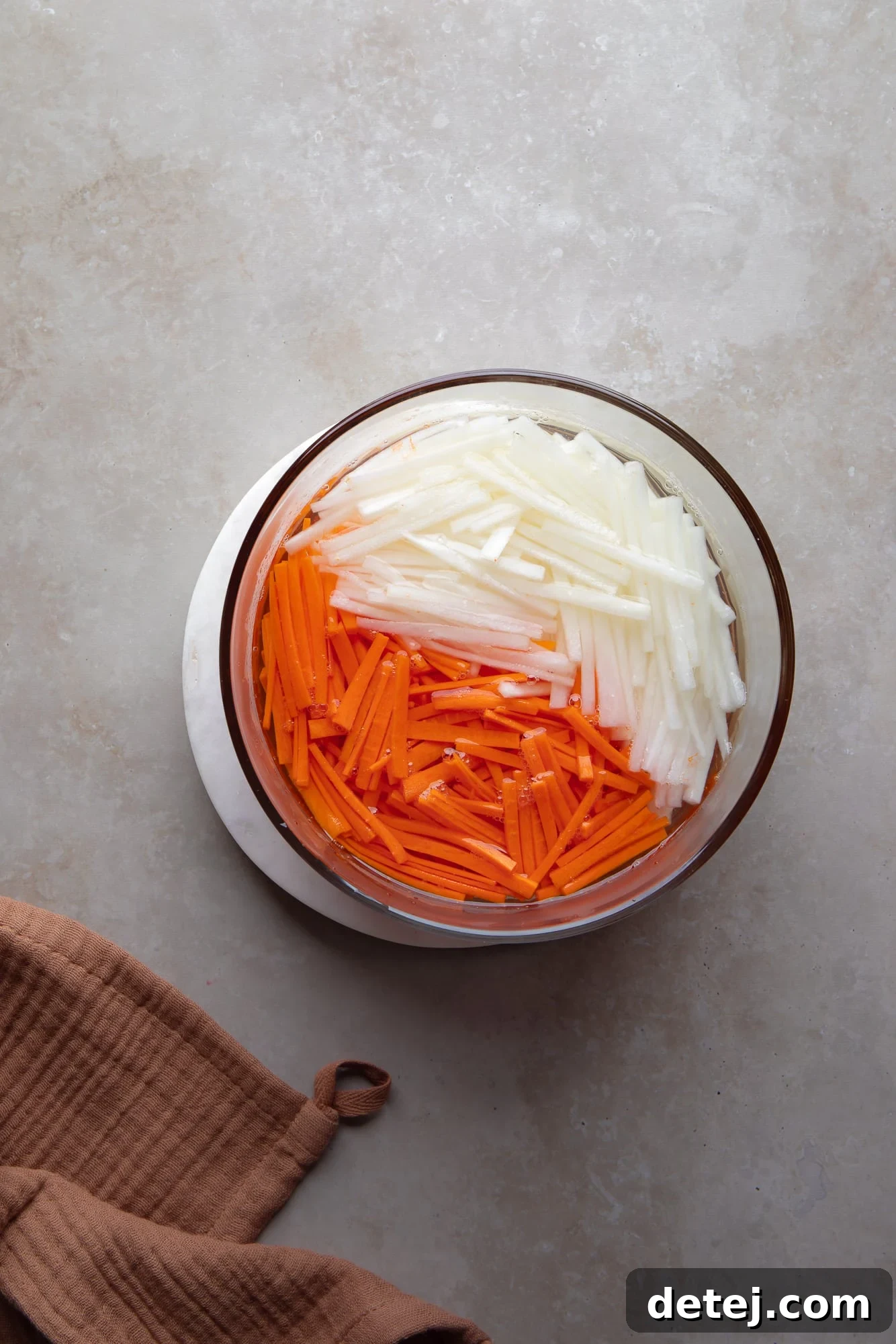 pickled carrot and daikon matchsticks in a glass container.