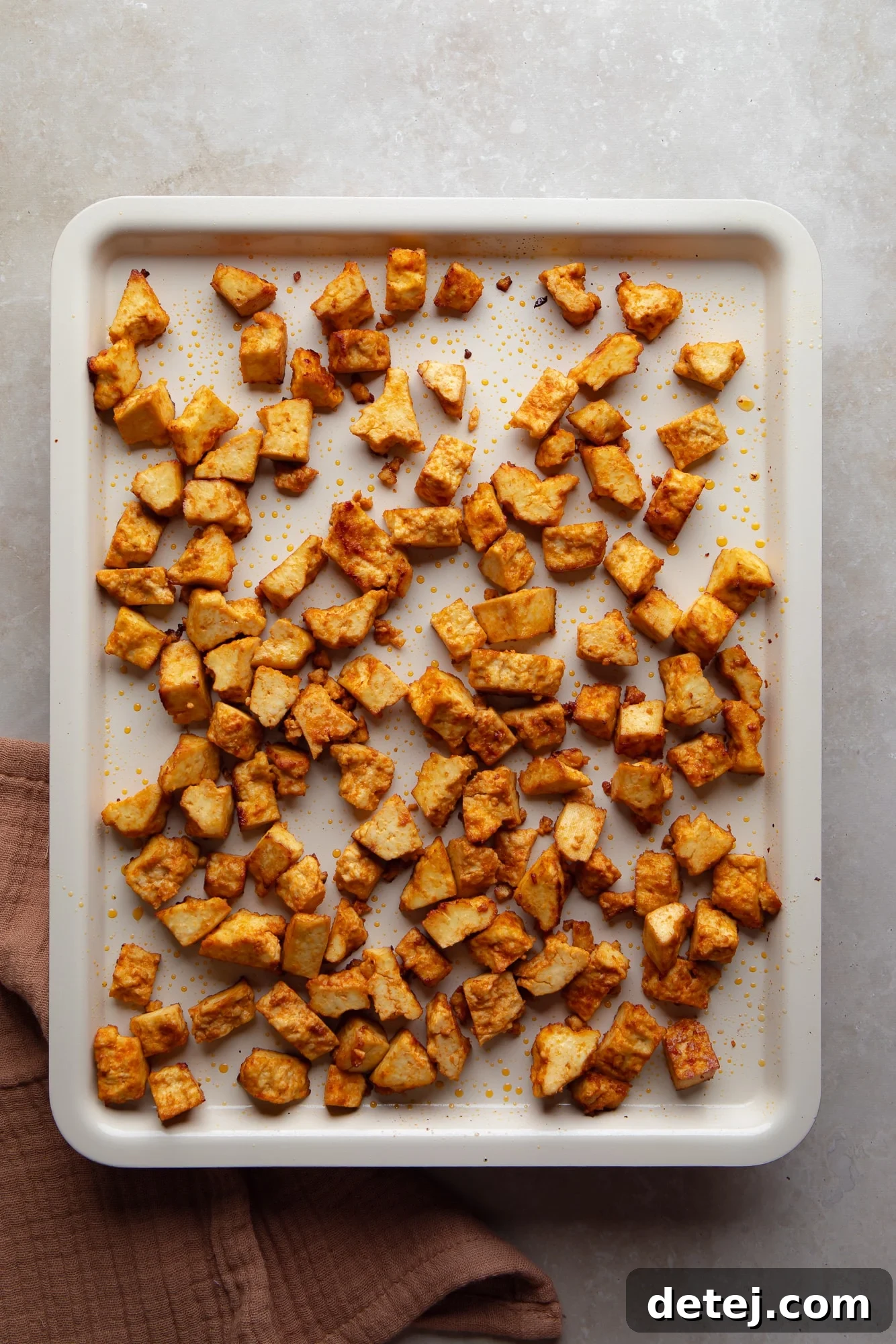 baked spicy tofu cubes on a white baking sheet.