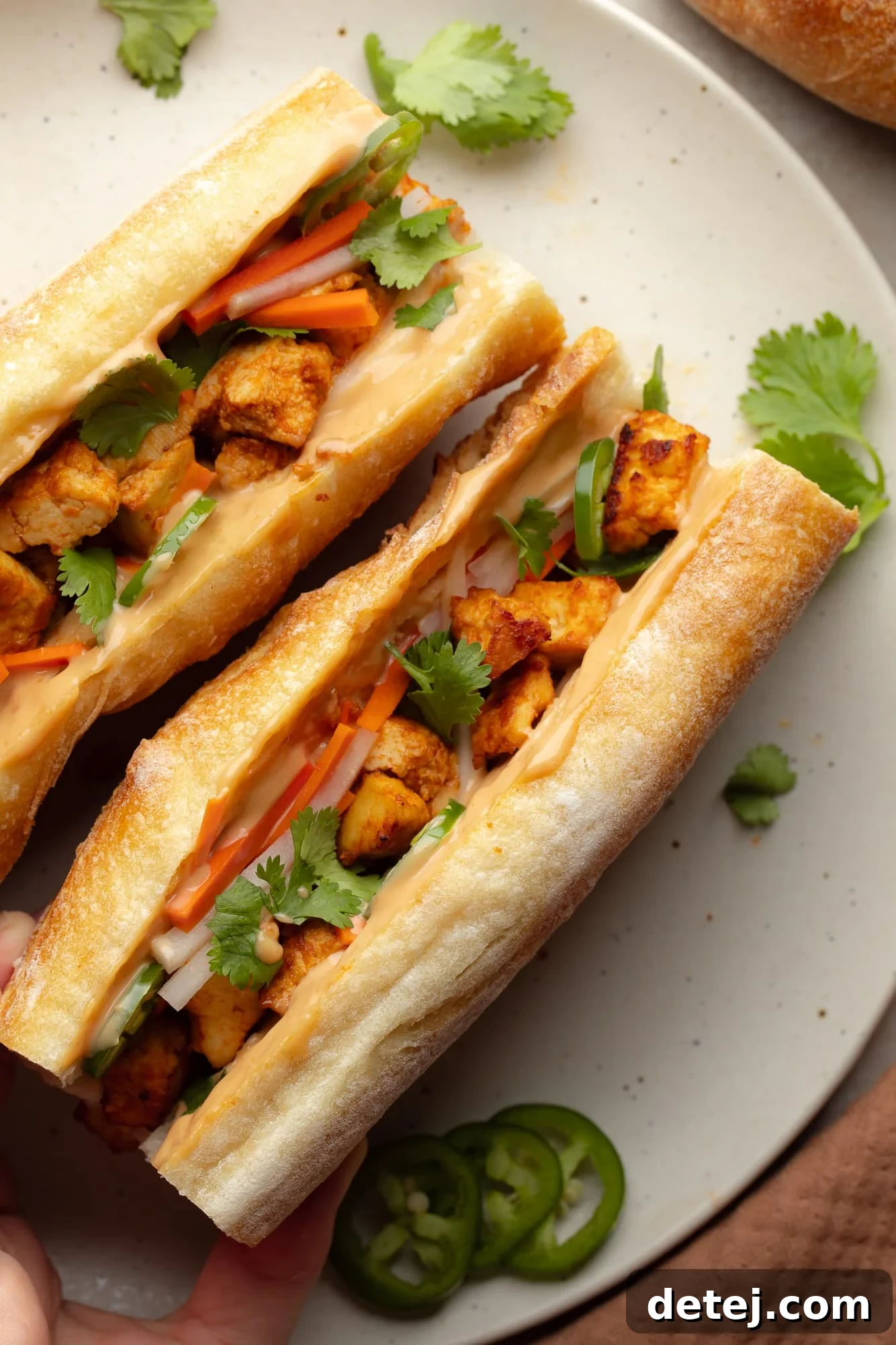 overhead view of two vegan banh mi sandwiches on a white plate.