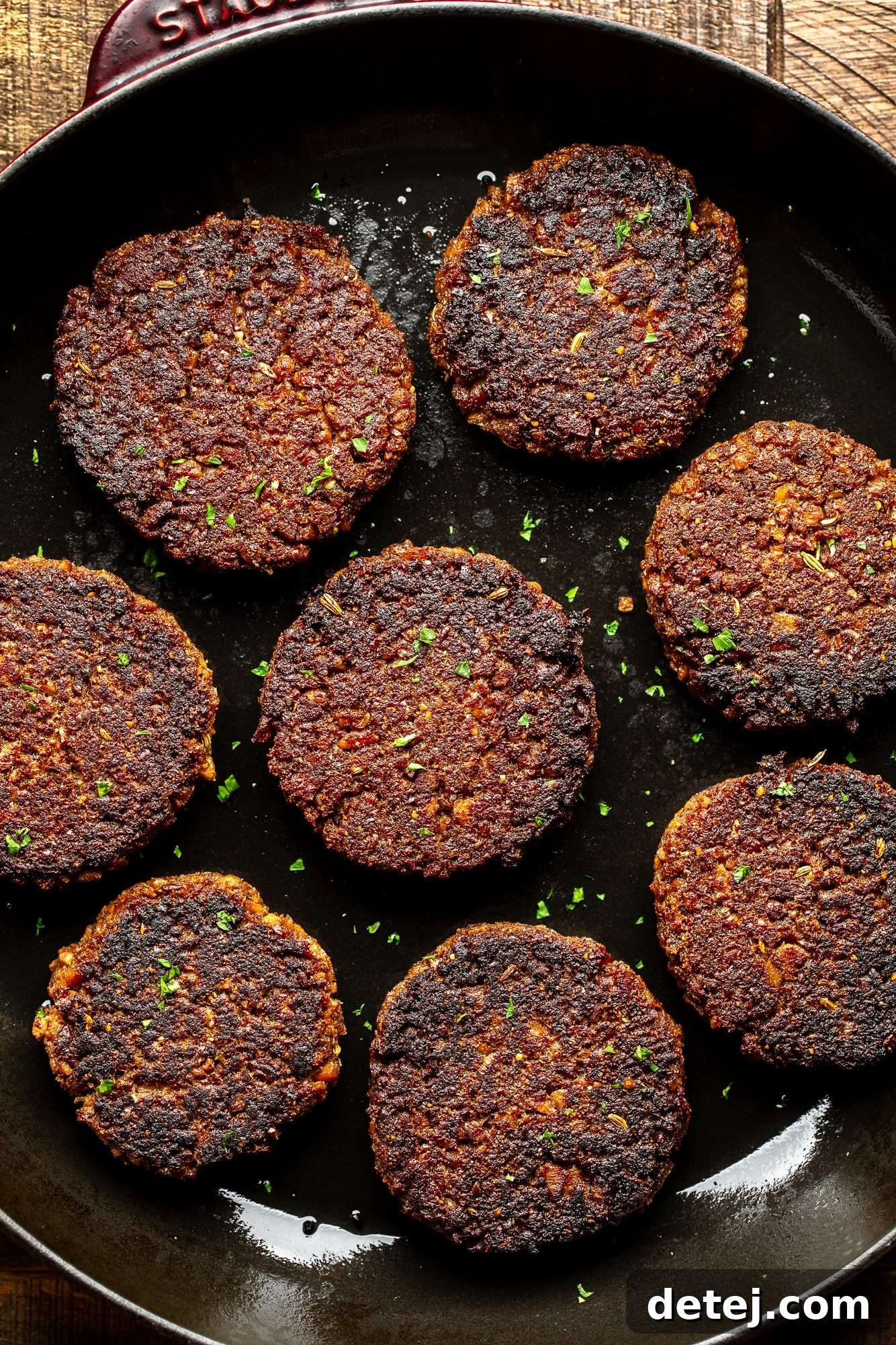vegan sausage patties frying in a large black skillet.