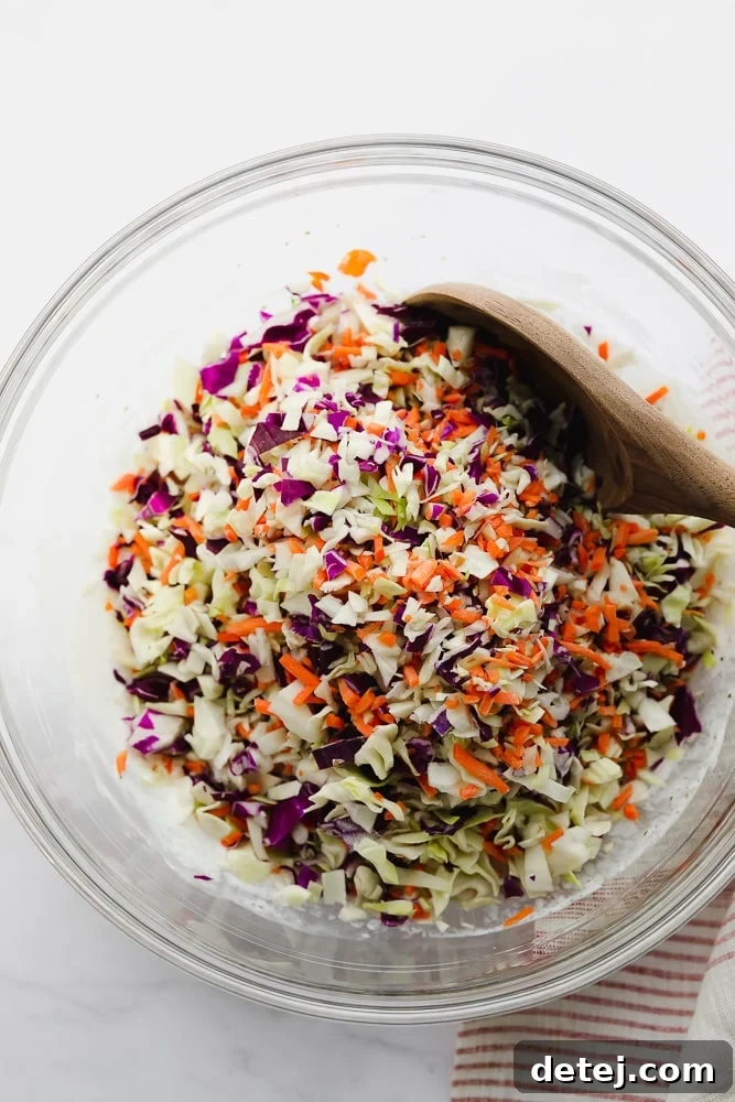 Shredded cabbage and carrots in a clear glass bowl, ready for the dressing.