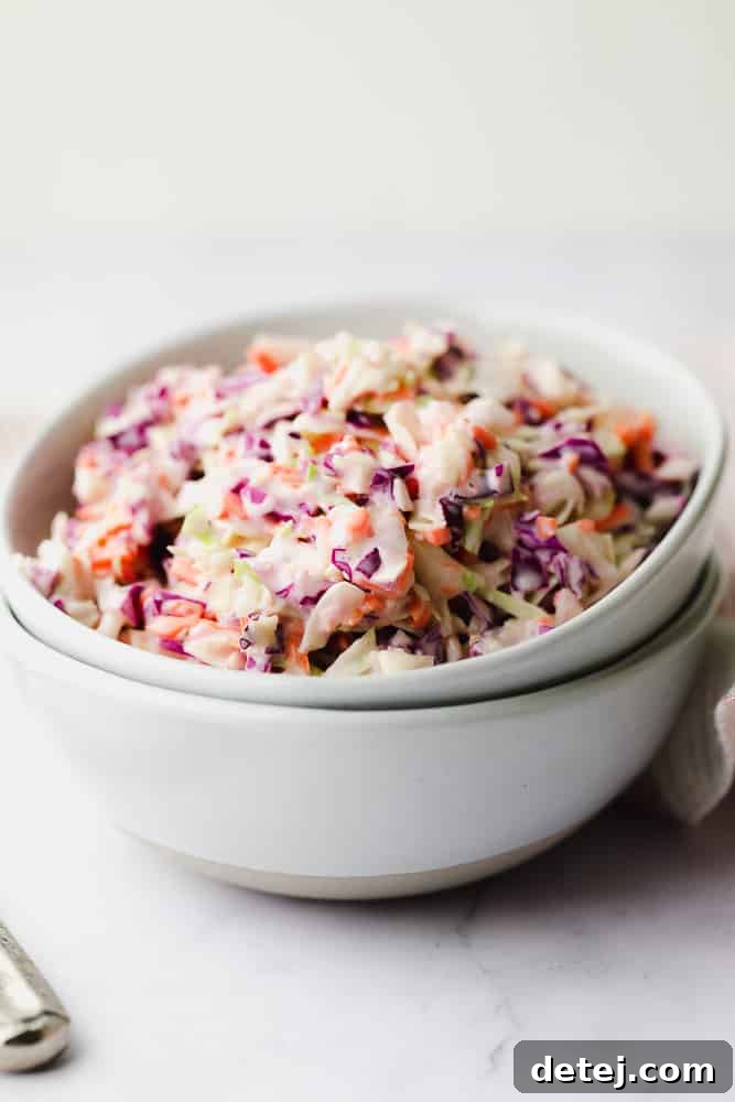 Two white bowls, one filled with a colorful mix of purple, orange, and green cabbage, resting inside each other.